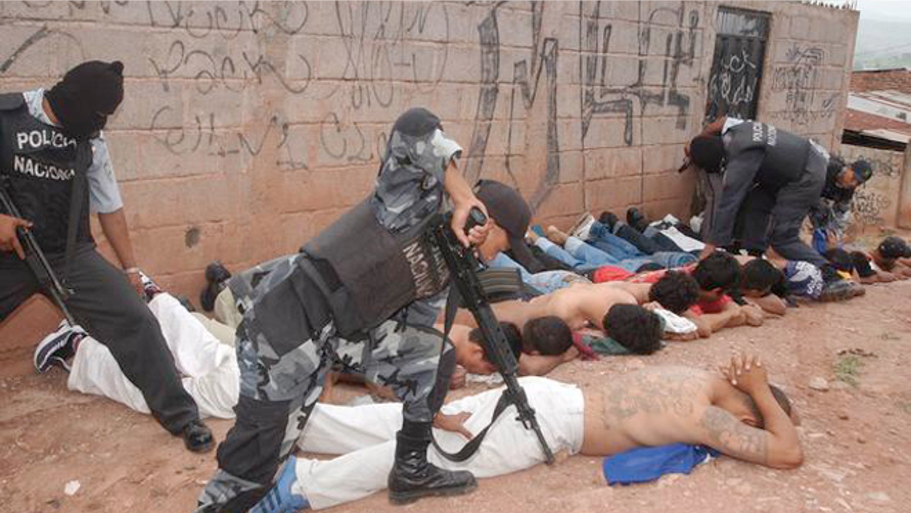 Police officers detain members of the Mara 18 and MS 13 gangs during the tour of President Ricardo Maduro and Security Minister Oscar Alvarez to the Colonia Bellavista neighborhood in Tegucigalpa, Honduras, Wednesday, July 2, 2003. The president sent a law to Congress on Tuesday, prohibiting gangs in the country.(AP Photo/Antonio Romero)