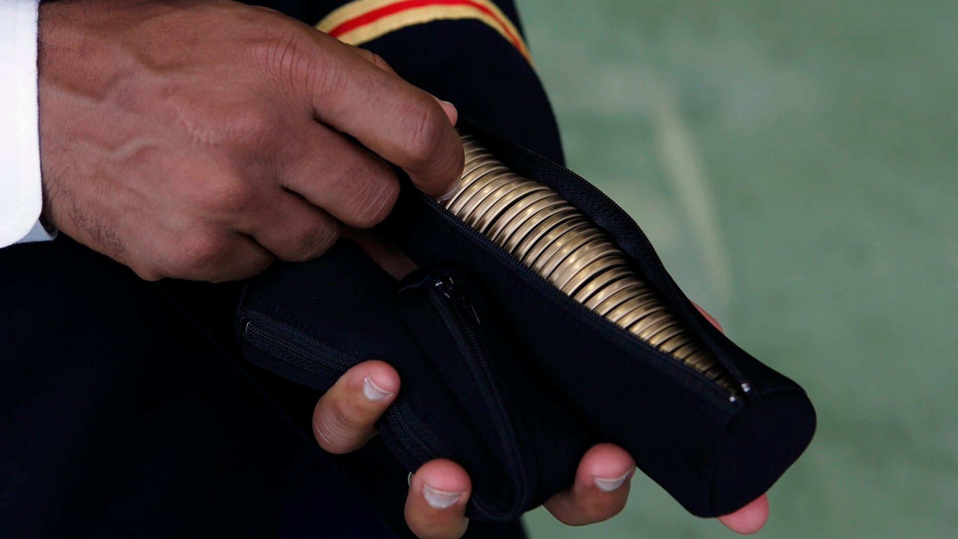 A U.S. Army officer holds a zippered pouch with "Challenge Coins" for Secretary of Defense Leon Panetta to hand out to U.S. military personnel stationed at Yokota Air Base in Japan, Sept. 17, 2012.