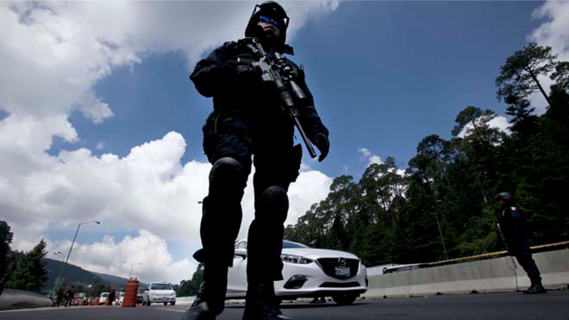 Federal Police patrol a checkpoint west of Mexico City, Thursday, July 16, 2015. A widespread manhunt that included highway checkpoints, stepped up border security and closure of an international airport failed to turn up any trace of drug lord Joaquin "El Chapo" Guzman after he escaped through an underground tunnel in his prison cell. (AP Photo/Marco Ugarte)