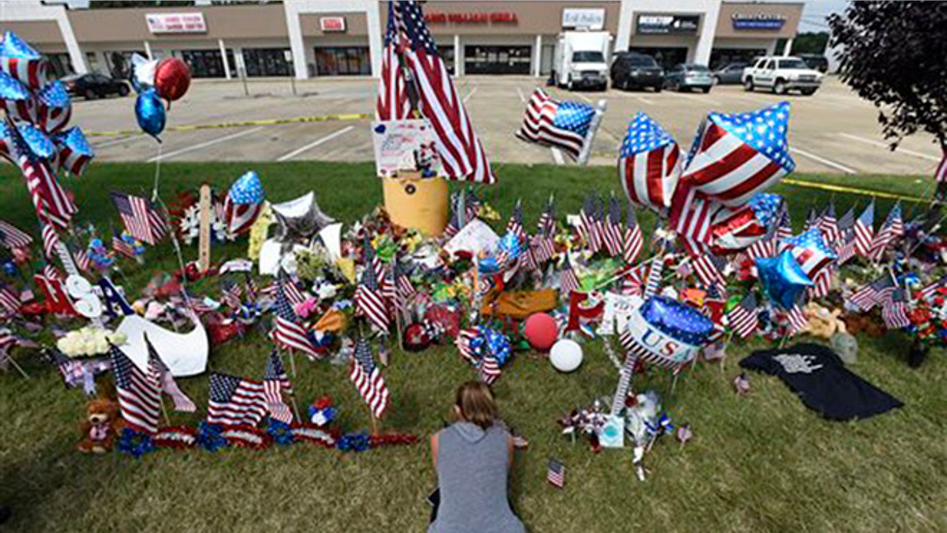 Daly Simmons, 26, sits as she prays in front of a makeshift memorial outside the Armed Forces Career Center Saturday, July 18, 2015, in Chattanooga, Tenn. Muhammad Youssef Abdulazeez, of Hixson, Tenn., attacked two military facilities on Thursday, in a shooting rampage that killed four Marines and one U.S. Navy sailor. (AP Photo/Mark Zaleski)