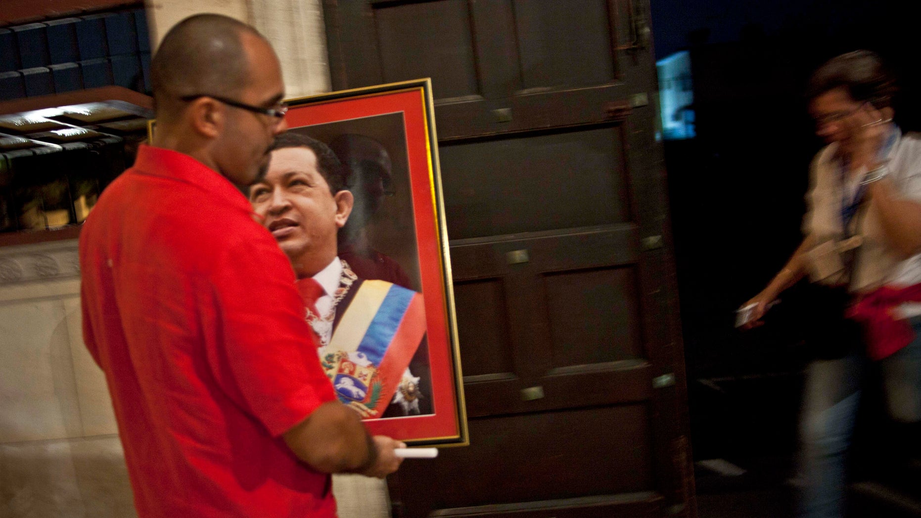 A man carries an image of Venezuela's President Hugo Chavez after a mass in support of him in Havana, Cuba, Thursday, Dec. 13, 2012. Chavez is recovering favorably despite suffering complications during cancer surgery in Cuba, his vice president Nicolas Maduro said Thursday amid uncertainty over the Venezuelan leader's health crisis and the country's political future. (AP Photo/Ramon Espinosa)