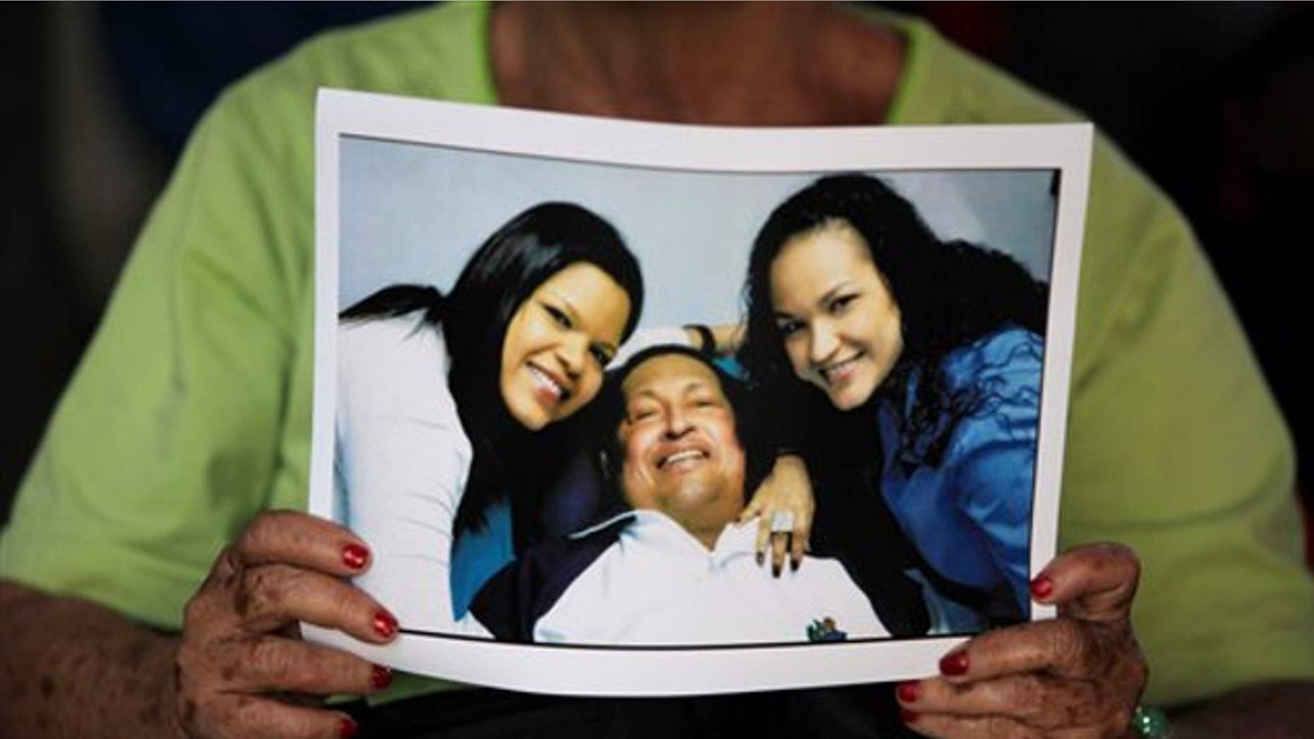 Feb. 15, 2013: A woman holds a newly purchased copy of a photo released by the government, showing Venezuela's President Hugo Chavez with two of his daughters, in Caracas,Venezuela.