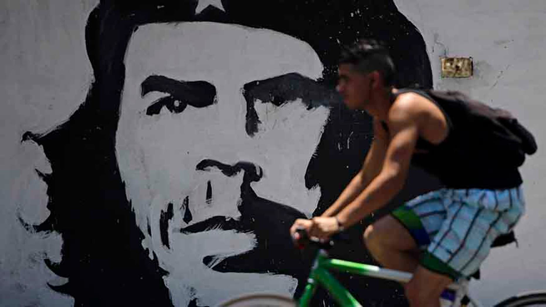 A man cycles beside a mural with the image of Cuban revolution leader Che Guevara in Havana, Cuba.