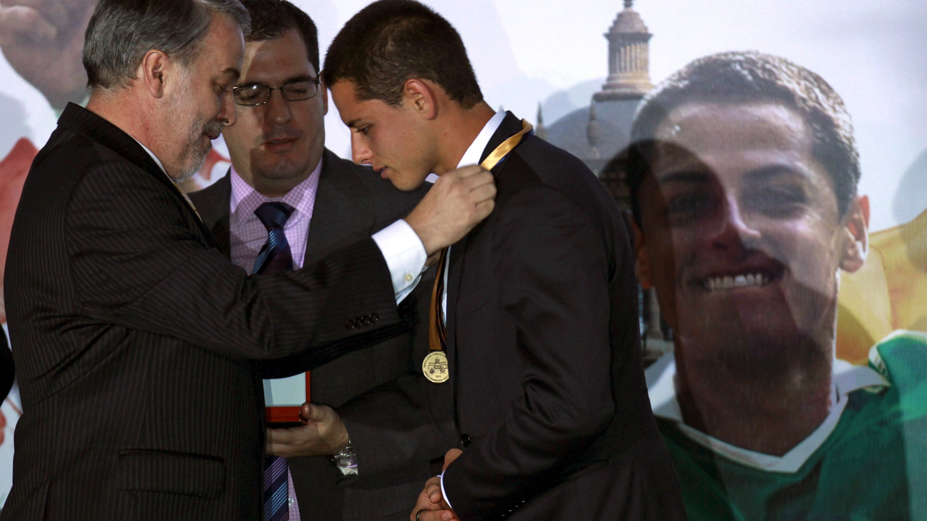 Mexican soccer player Javier "Chicharito" Hernandez, right, is awarded a medal from the governor of the state of Jalisco, Emilio Gonzalez Marquez, during a ceremony in which Chicharito was named the 2011 Tourism Ambassador for the State of Jalisco, in Guadalajara, Mexico Thursday July 21, 2011. Chicharito currently plays for the English football club Manchester United. (AP Photo/Bruno Gonzalez)