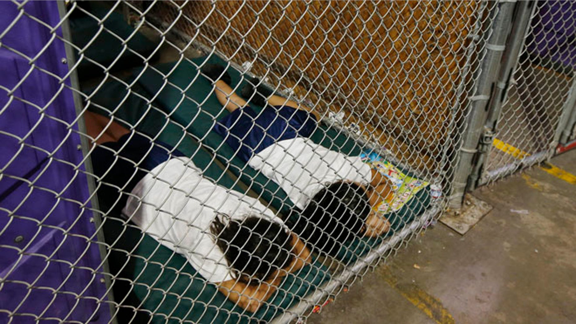 Two female detainees sleep in a holding cell, as the children are separated by age group and gender, as hundreds of mostly Central American immigrant children are being processed and held at the U.S. Customs and Border Protection (CBP) Nogales Placement Center in Nogales, Arizona, June 18, 2014.