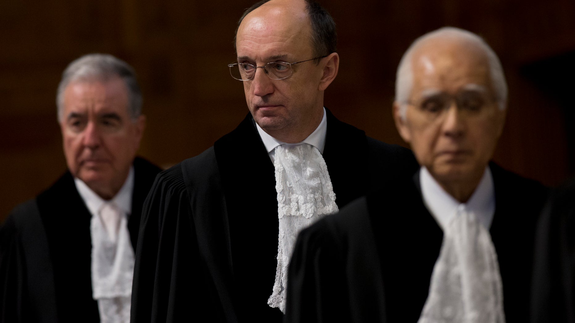 Presidente Peter Tomka de Eslovaquia, centro, juez Hisashi Owada de Japón, derecha y vicepresidente Bernado Setulveda-Amor de México toman asiento para leer el fallo de la Corte Internacional de Justicia de la Haya sobre el diferendo marítimo entre Chile y Perú, lunes 27 de enero de 2014. La corte superior de las Naciones Unidas trazó el lunes una nueva frontera marítima entre Perú y Chile que otorga a Perú parte de la zona disputada del Océano Pacífico pero deja en manos chilenas la rica zona pesquera. (AP Foto/Peter Dejong)