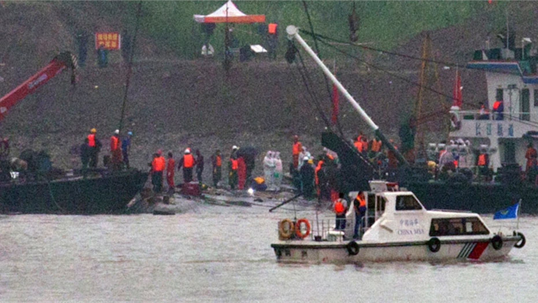 June 4, 2015: A marine boat patrols past as rescuers work on the capsized ship, center, on the Yangtze River in Jianli county of southern Chinas Hubei province, as seen from across the river from Huarong county of southern Chinas Hunan province. Rescuers cut into the upside-down hull of the river cruise ship and pulled out drowned passengers early Thursday.