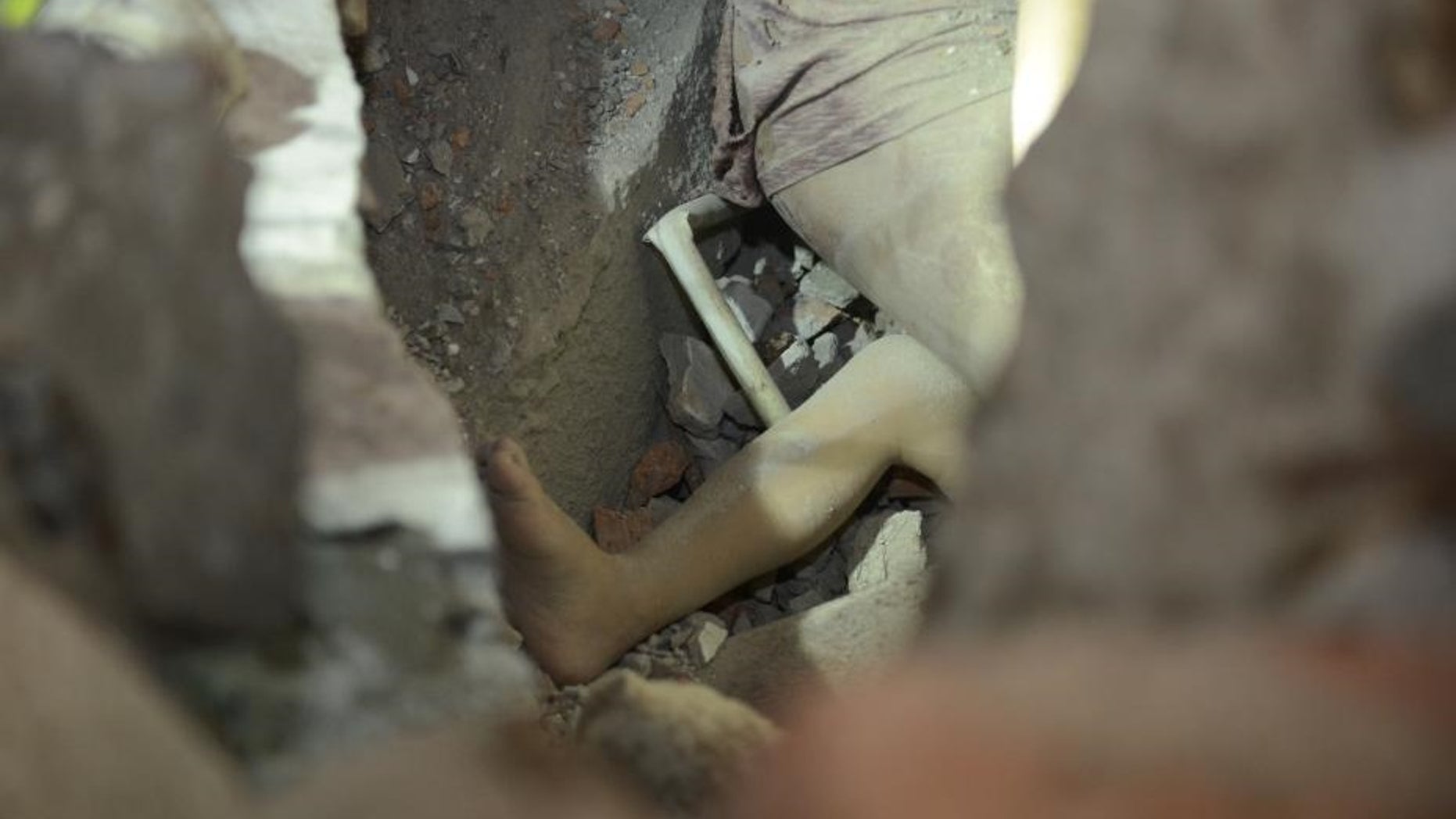 One leg of a young girl who survived the collapse of buildings is seen in the rubble.