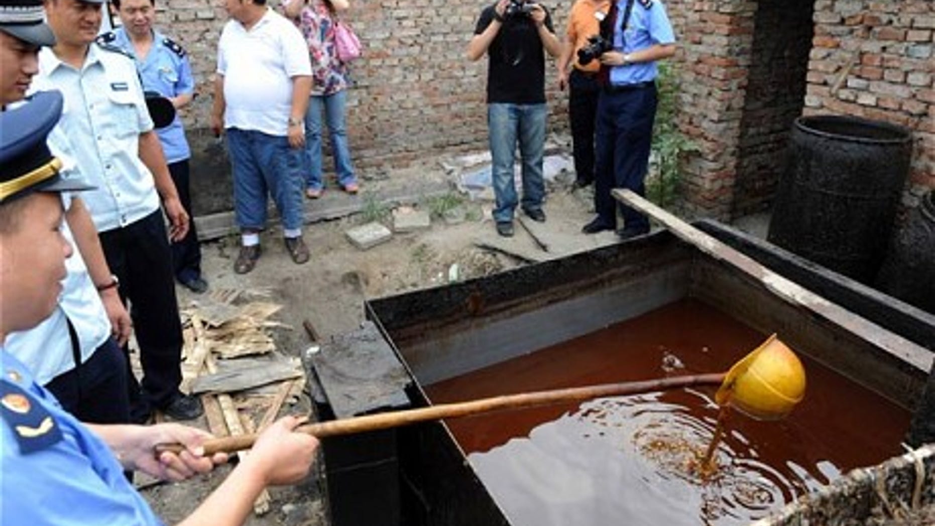 Police inspect illegal cooking oil, better known as "sewer oil" seized during a crackdown in Beijing.