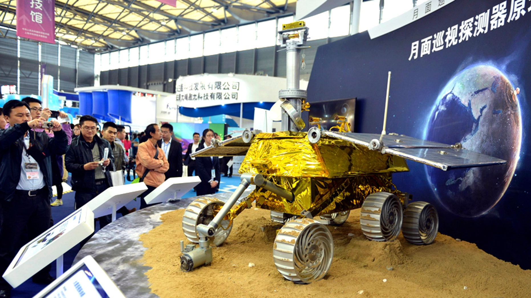 Visitors take pictures of a prototype model of a lunar rover at the 15th China International Industry Fair in Shanghai, November 5, 2013. China will land its first probe on the moon in early December which will deploy a buggy to explore its surface, an official said on November 26, marking a major milestone in the country's space ambitions.
