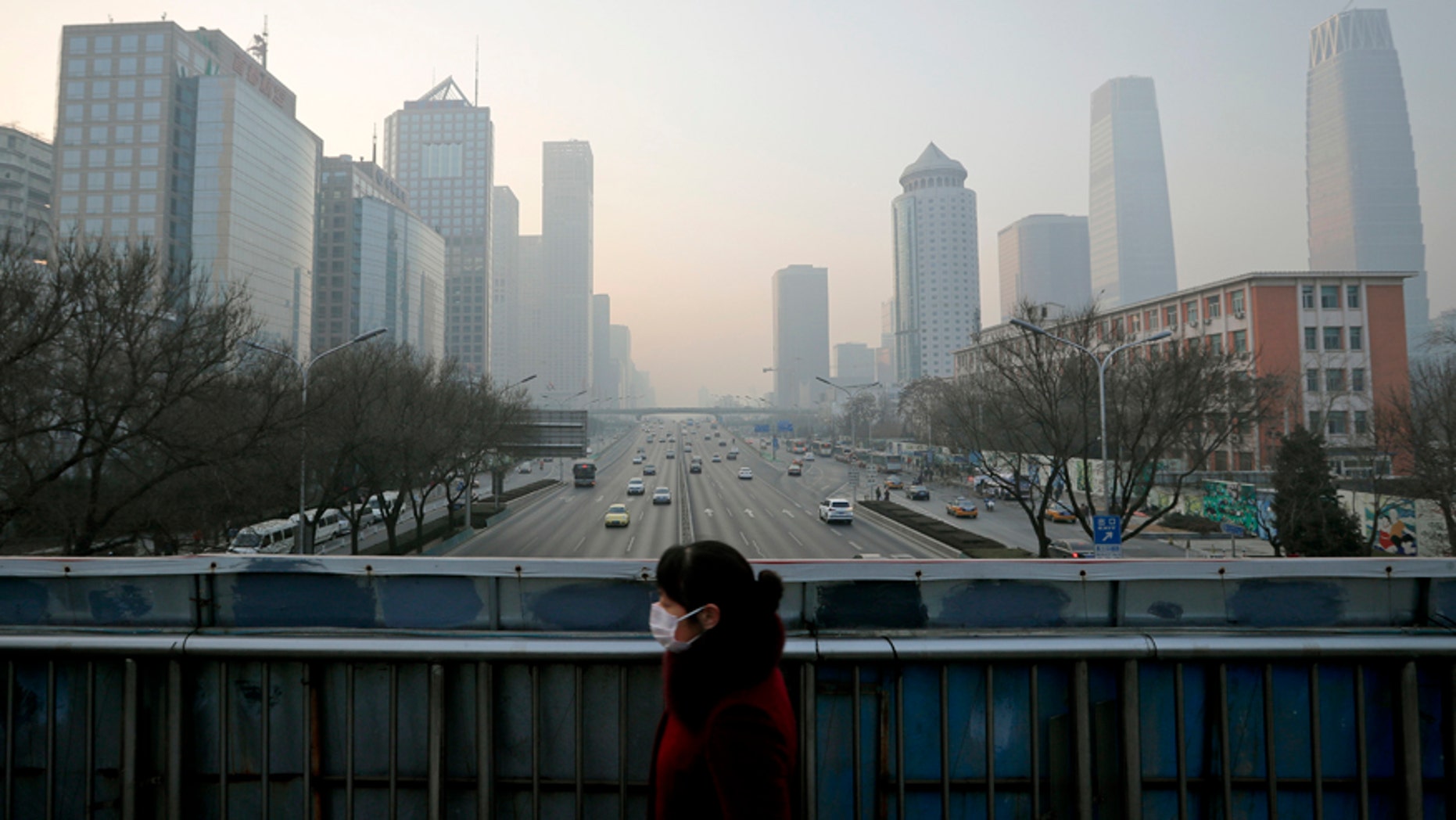 A woman wearing a mask for protection against air pollution walks on a pedestrian overhead bridge in Beijing as the capital of China is shrouded by heavy smog Monday, Dec. 19, 2016.