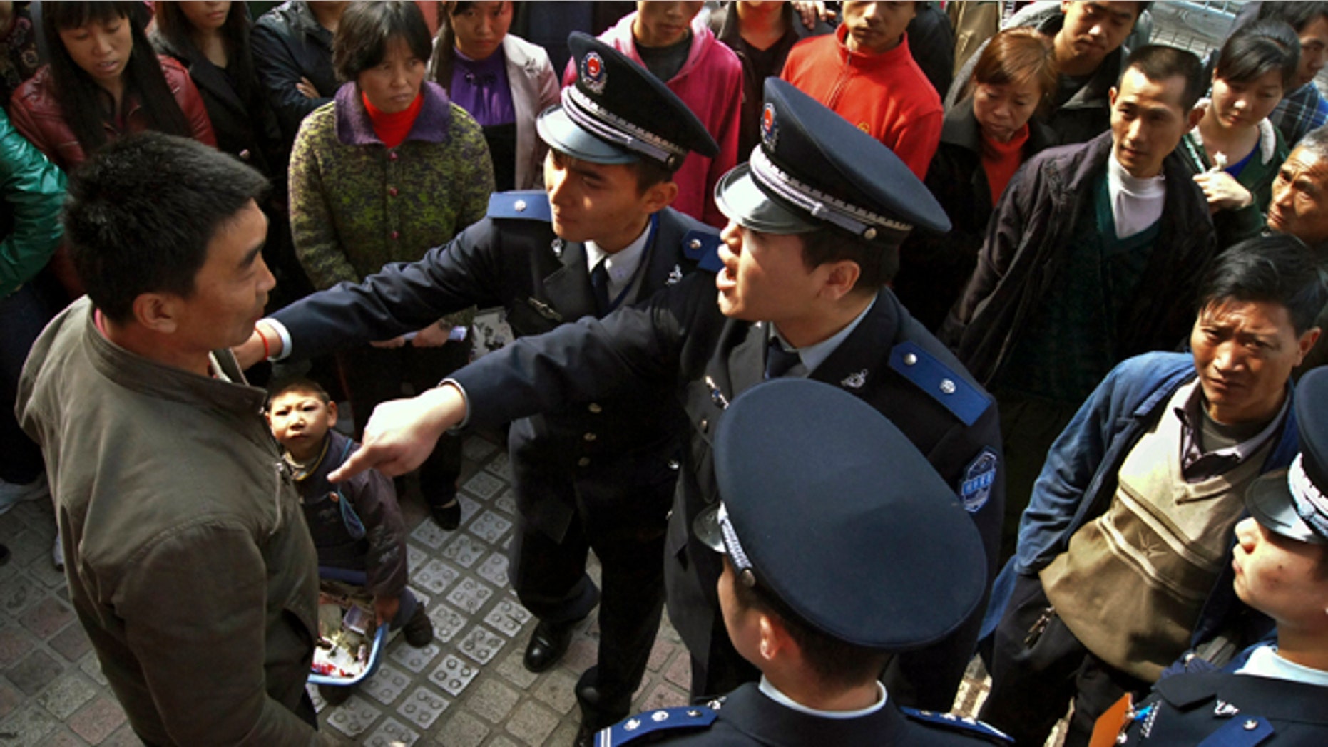Nov. 20, 2011: Officers of the urban management bureau, known as chengguan in Chinese, demand a beggar and his child to leave a street in Guiyang, in southwestern China's Guizhou province.