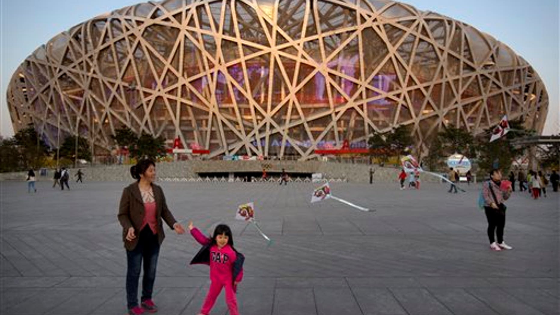 In this March 28, 2015 photo, a girl flies a kite on Olympic Green near Beijing National Stadium, also known as the Birds Nest and the site of track and field events during the 2008 Beijing Olympics, in Beijing. (AP Photo/Mark Schiefelbein)