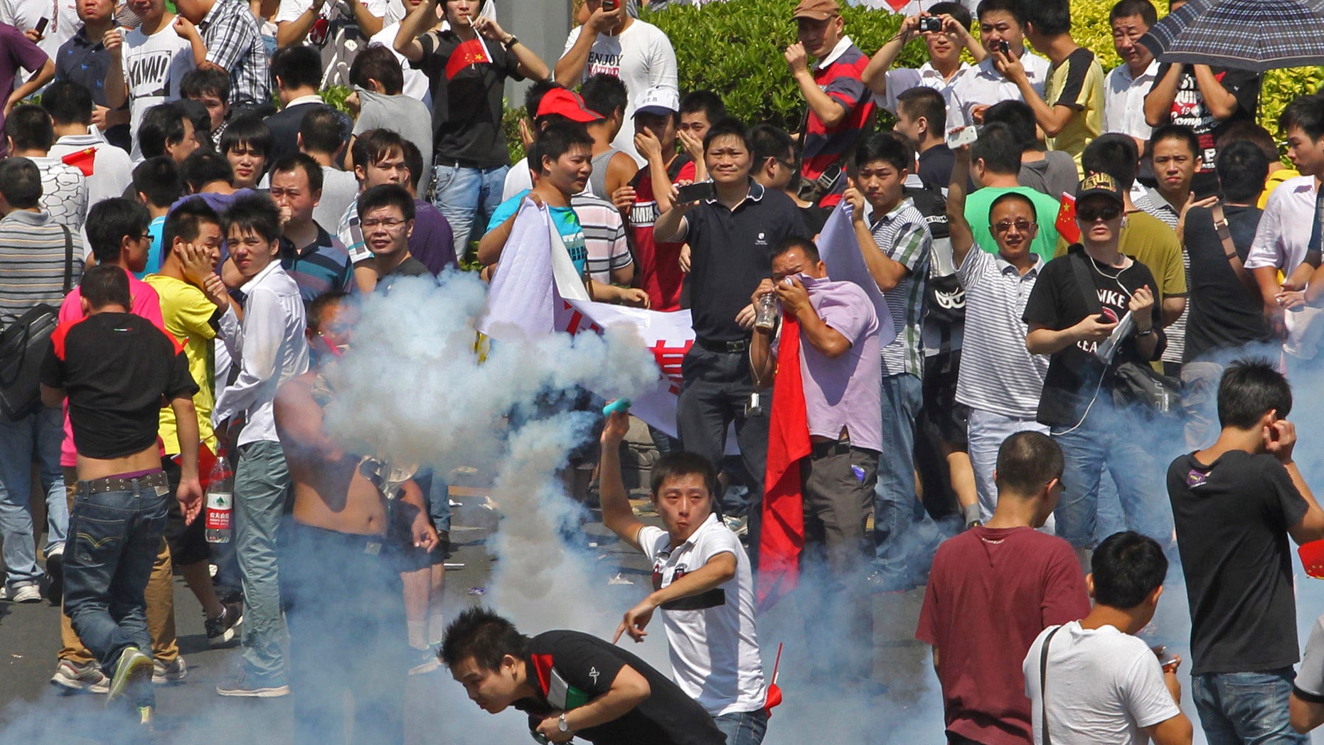 Sept. 16, 2012: A Chinese demonstrator throws a teargas canister back to riot policemen during a protest against Japan in Shenzhen, China.