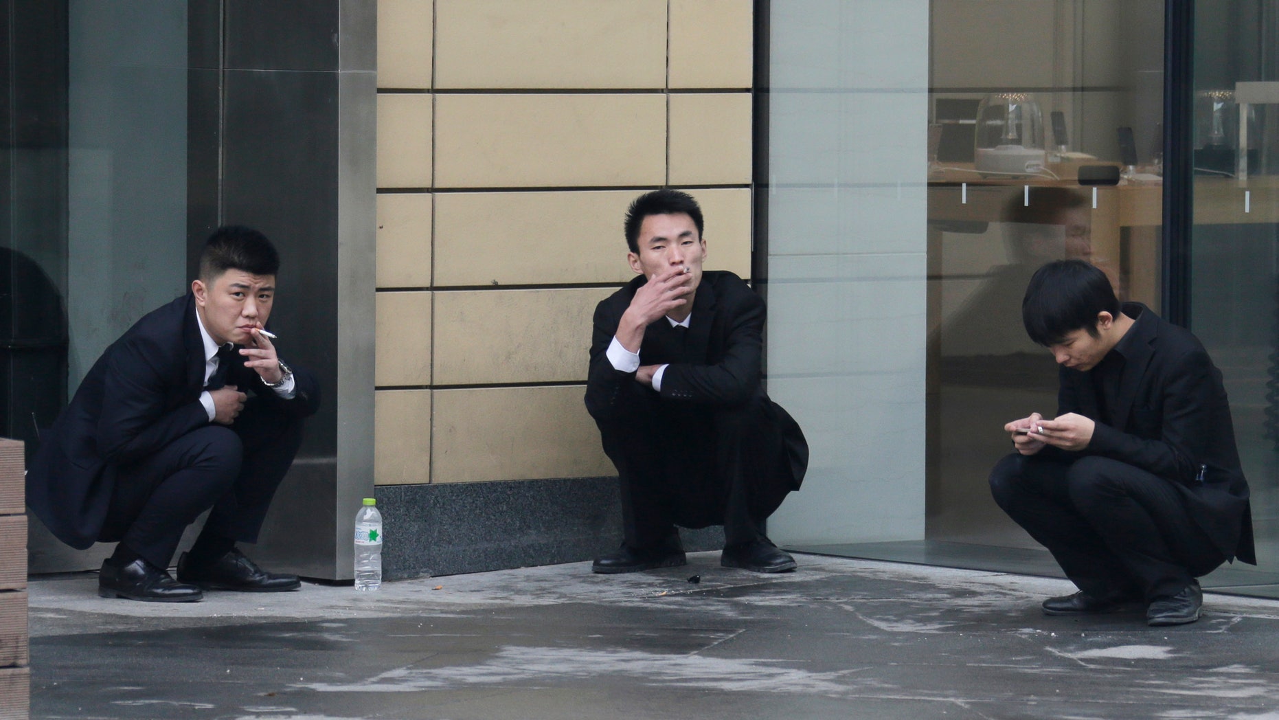 Employees smoke outside an office building in Beijing, November 25, 2014. REUTERS/Jason Lee