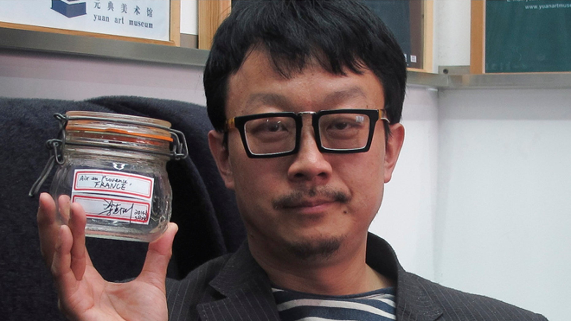 April 5, 2014: In this photo, Beijing artist Liang Kegang poses with the jar of fresh air collected in Provence, France, in an art gallery in Beijing, China.