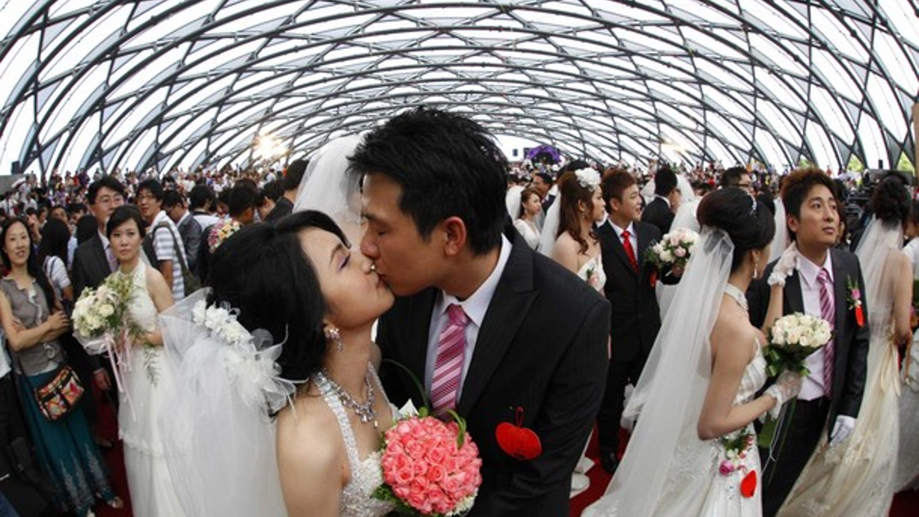 Zheng Ya-yuan (L), 32, and Chang Hong-chang, 31, who have been dating for six years, kiss during a mass wedding ceremony at the Taipei Flora Expo Hall September 9, 2010. A mass wedding ceremony was held for 163 couples on Thursday on the ninth day of the ninth month in the 99th year since the beginning of the Republic of China (Taiwan). The date which makes out to 9.9.99 is an auspicious number as the number ���9��� (pronounced jiu in Chinese) is a homophone that means lasting. REUTERS/Nicky Loh (TAIWAN - Tags: SOCIETY IMAGES OF THE DAY)