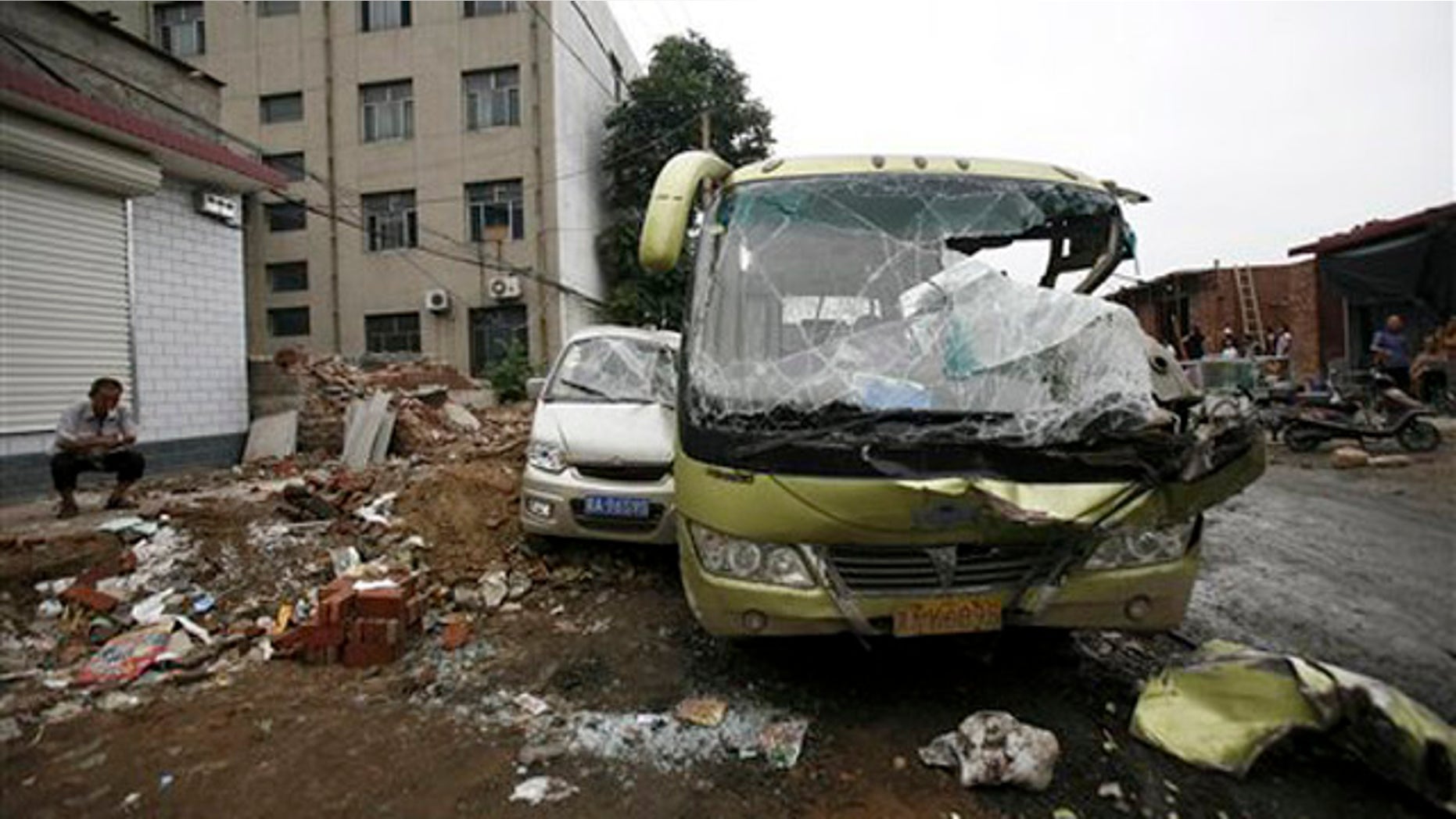 Aug. 1, 2010: Man smokes near smashed vehicles at Yuanshi county, in north China's Hebei province. A drunken shovel loader driver went on a rampage in northern China, smashing into shops and vehicles and killing 11 people, a government spokesman said Monday.