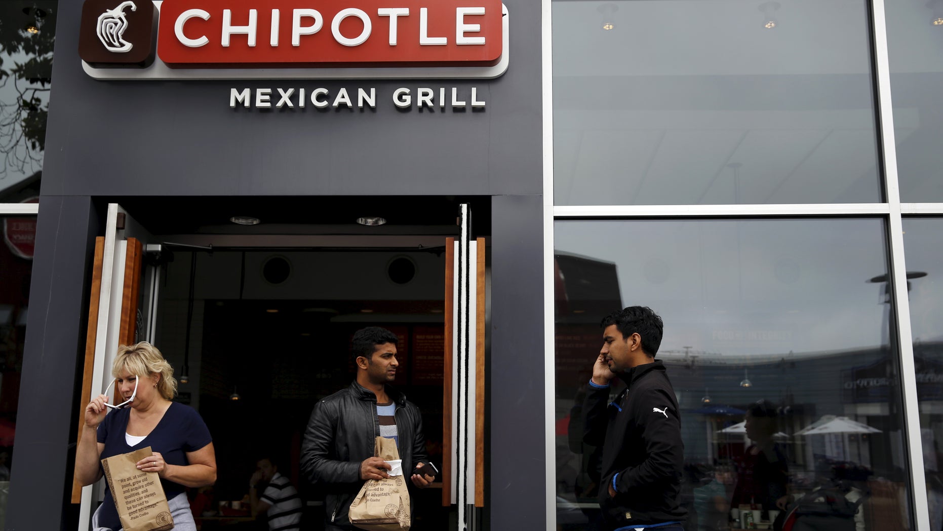 People carry bags as they leave a Chipotle Mexican Grill restaurant in San Francisco, California July 21, 2015. Burrito chain Chipotle Mexican Grill Inc reported lower-than-expected quarterly revenue on Tuesday. REUTERS/Robert Galbraith