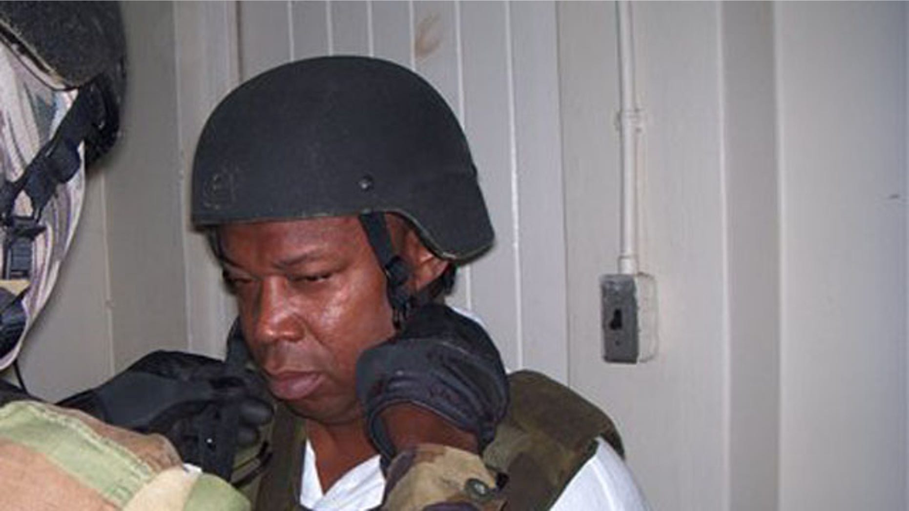 Christopher "Dudus" Coke, seen here being fit for a bulletproof vest moments after arrest, has been sentenced to 23 years in jail for drug trafficking by New York courts. (AP)