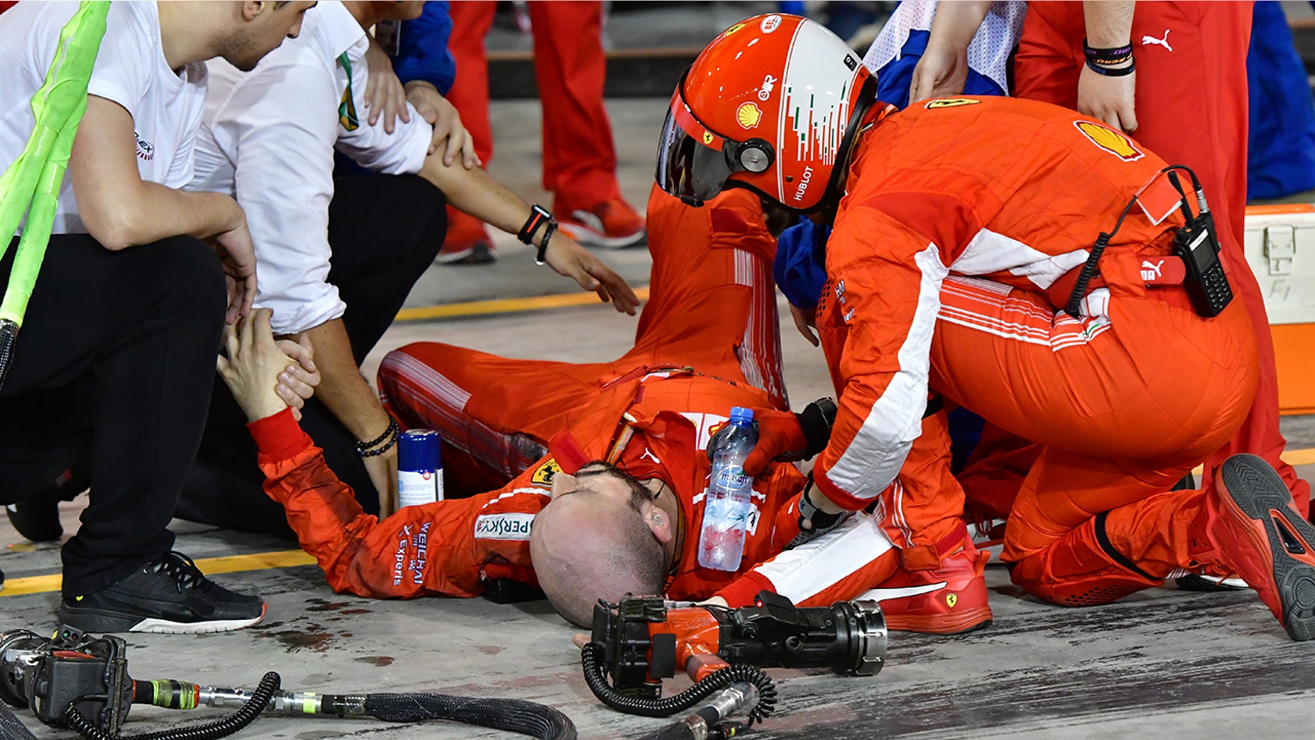 Teammates aid Francesco Cigarini after he was hit by Kimi Raikonnen's F1 car.