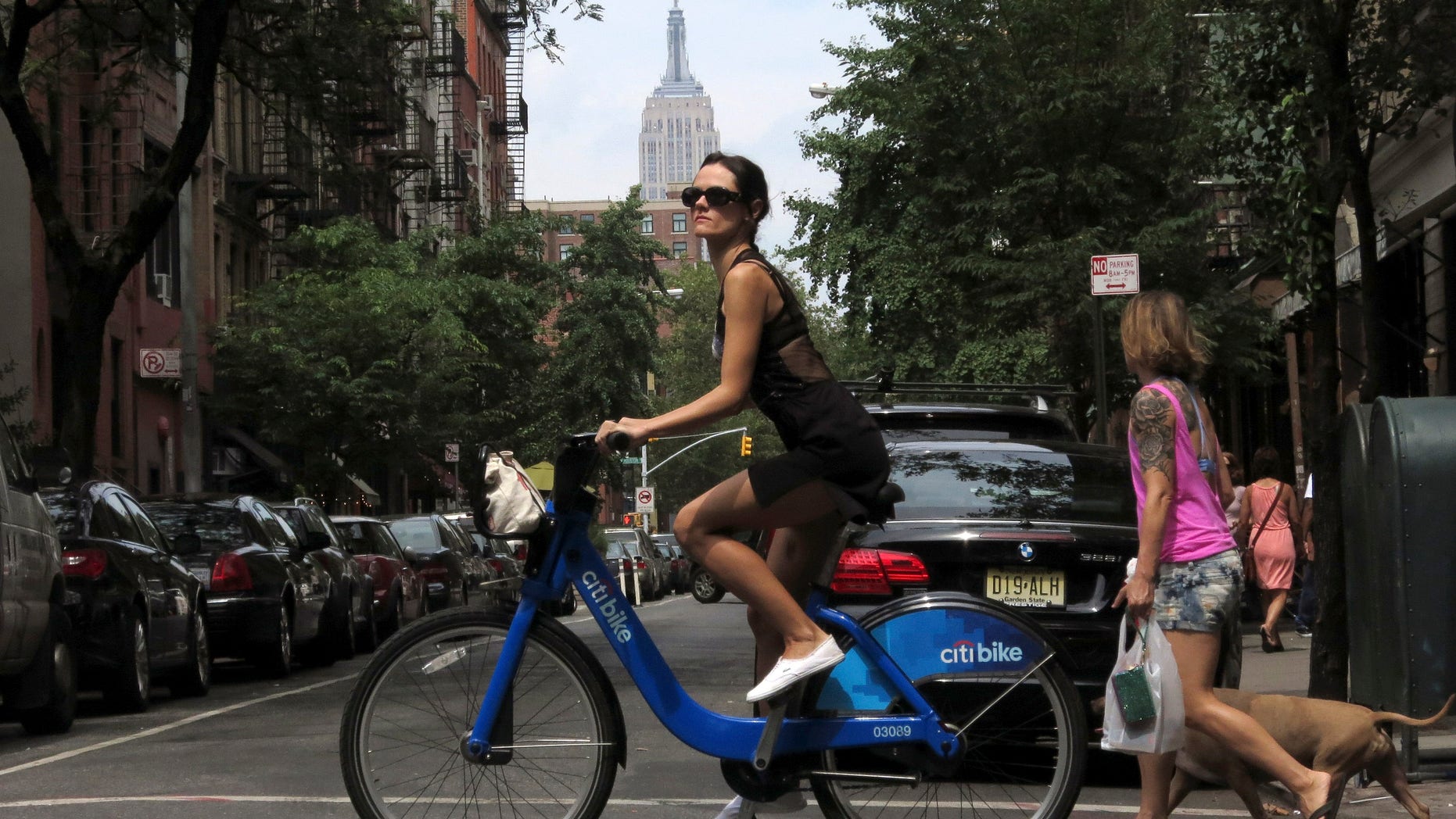 The Empire State Building is seen in the distance as a woman rides a Citibike in the Soho neighbourhood of New York July 27, 2013. REUTERS/Gary Hershorn