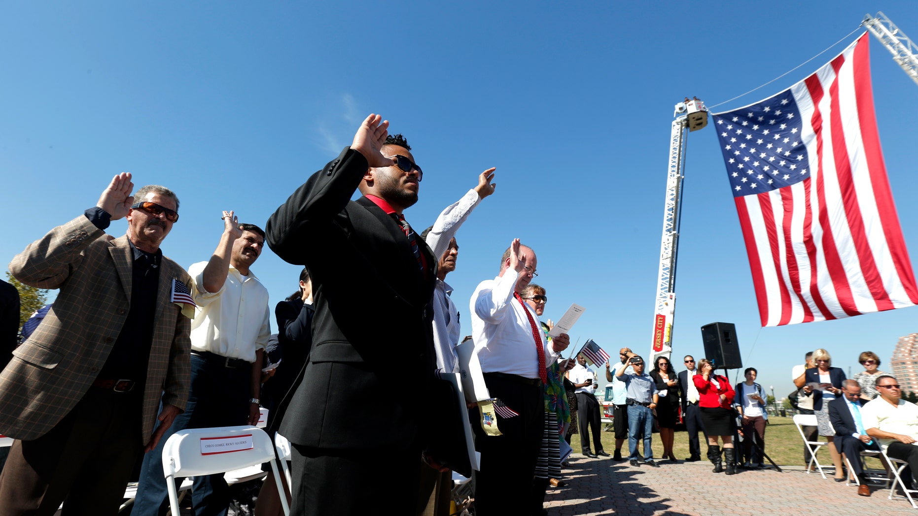 Ricky Checo, center, of the Dominican Republic, takes the oath of allegiance along with other immigrants during a citizenship ceremony at Liberty State Park, Thursday, Sept. 17, 2015, in Jersey City, N.J. Constitution Day and Citizenship Day is celebrated each year on Sept. 17, on the anniversary of the signing of the Constitution in 1787. The U.S. Citizenship and Immigration Services is expected to welcome more than 36,000 new citizens during more than 200 naturalization ceremonies across the country from Sept. 17-23. (AP Photo/Julio Cortez)