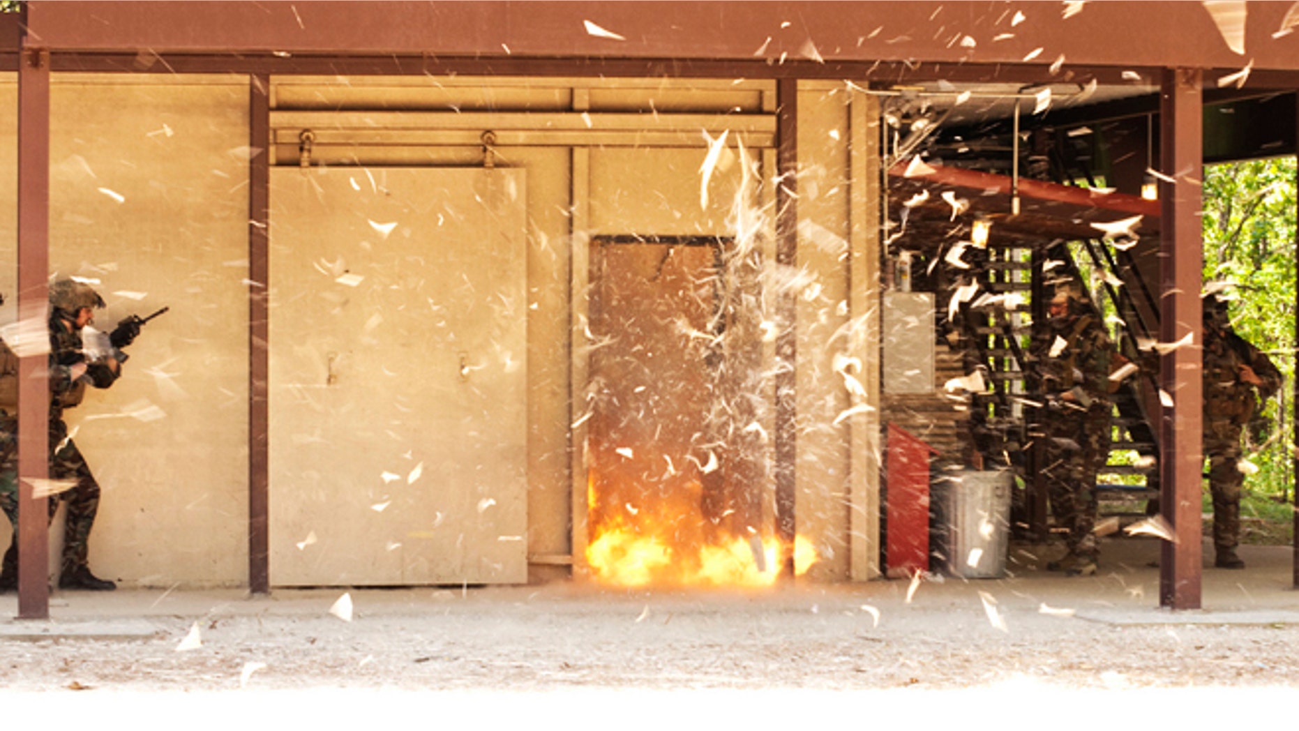Special operations soldiers stand clear as they blow a door open to demonstrate how they clear buildings during a training exercise.