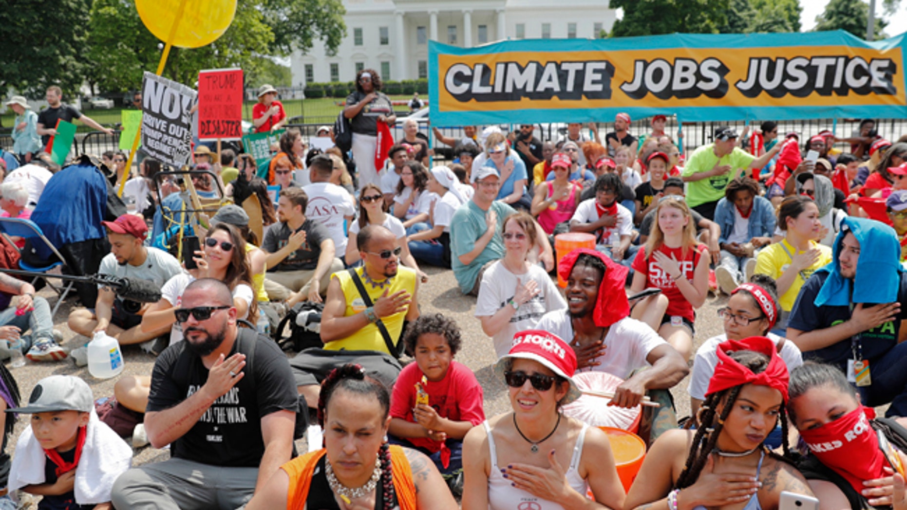 Demonstrators sit on the ground along Pennsylvania Ave. in front of the White House in Washington, Saturday, April 29, 2017, during a demonstration and march. Thousands of people gathered across the country to march in protest of President Donald Trump's environmental policies, which have included rolling back restrictions on mining, oil drilling and greenhouse gas emissions at coal-fired power plants.