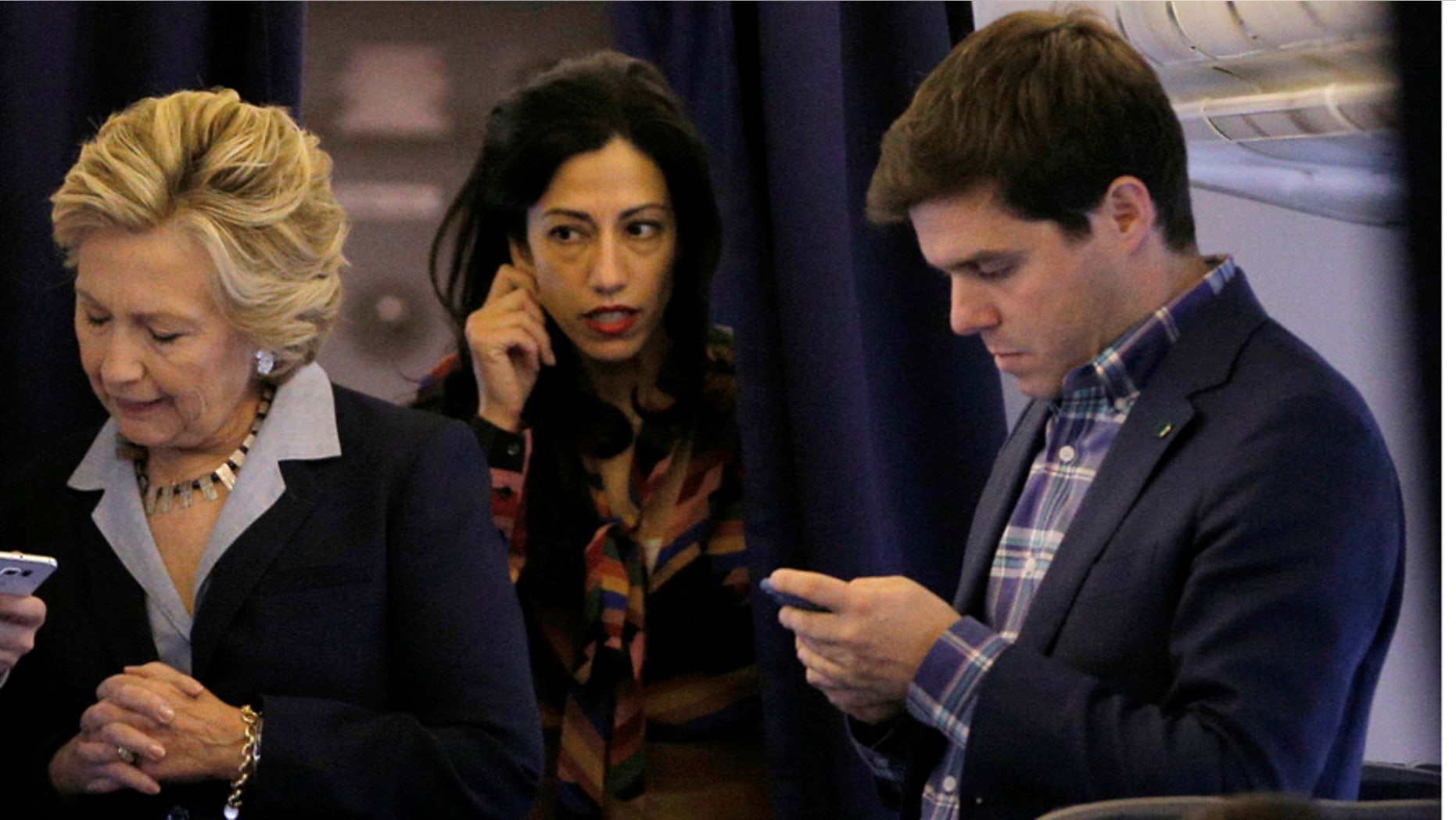 Hillary Clinton stands with longtime aide Huma Abedin, middle, and press secretary Nick Merrill, right, onboard her campaign plane in October 2016.