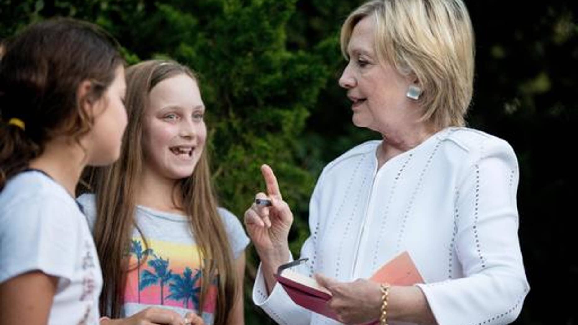 Democratic presidential candidate Hillary Clinton speaks with neighborhood children as she signs a book for them following a fundraiser at a private home in Sagaponack, N.Y., Tuesday, Aug. 30, 2016. (AP Photo/Andrew Harnik)