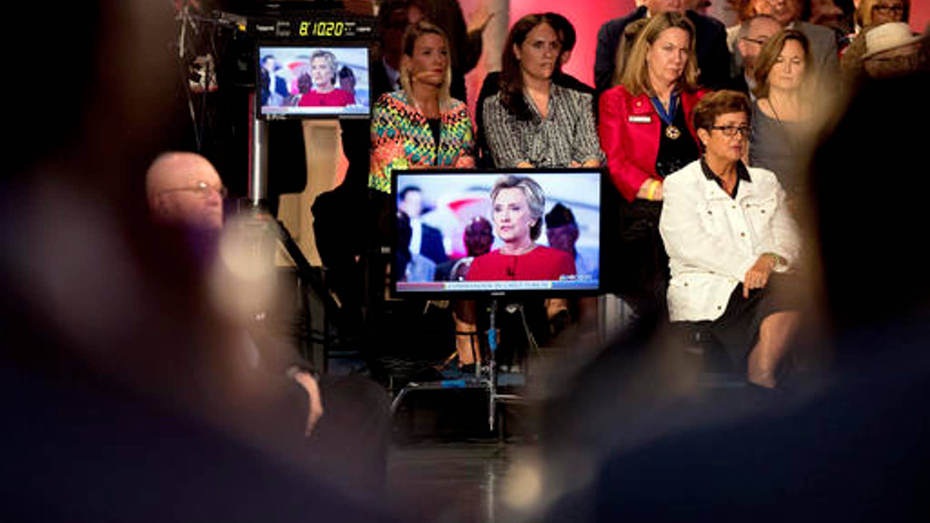 Members of the audience listen to Democratic presidential candidate Hillary Clinton, displayed on television screens as she speaks with 'Today' show co-anchor Matt Lauer at the NBC Commander-In-Chief Forum held at the Intrepid Sea, Air and Space museum aboard the decommissioned aircraft carrier Intrepid, New York, Wednesday, Sept. 7, 2016.