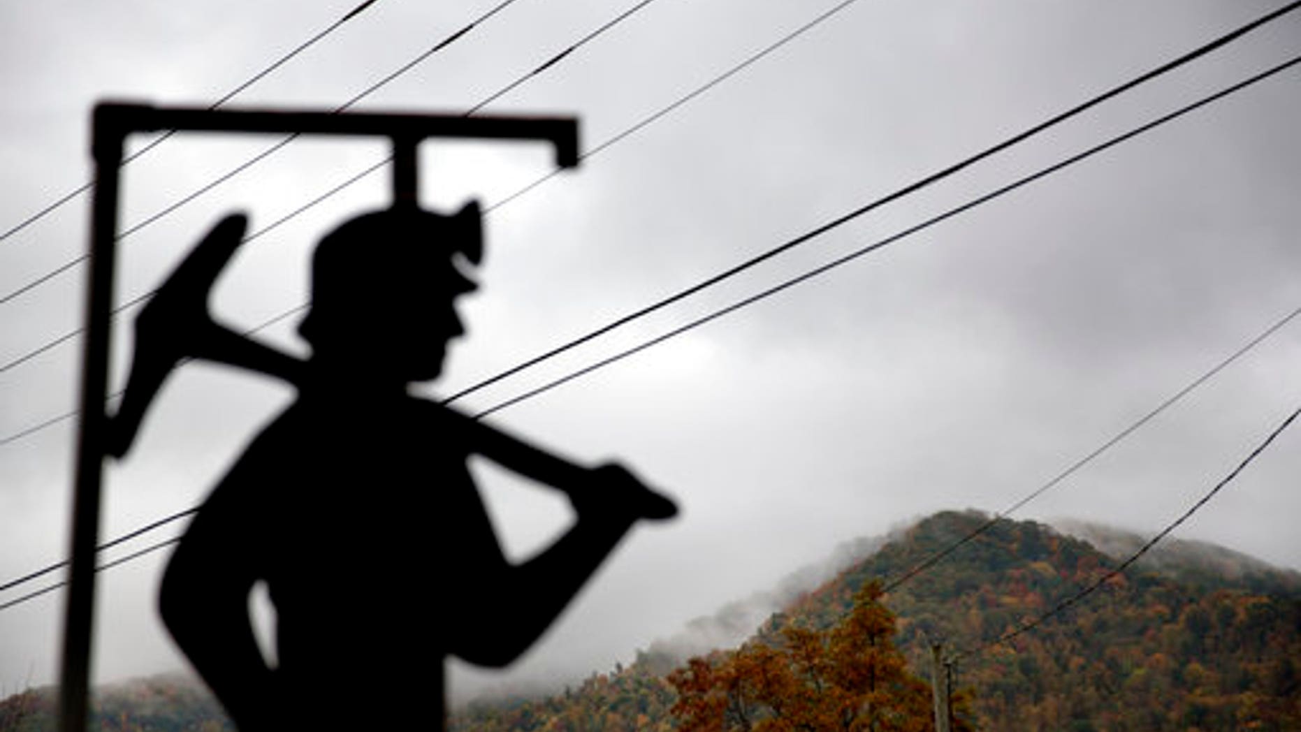 FILE - In this Oct. 16, 2014 file photo, fog hovers over a mountaintop as a cutout depicting a coal miner stands at a memorial to local miners killed on the job in Cumberland, Ky. The Republican-controlled Kentucky state legislature is on the cusp of lifting its decades-long moratorium on nuclear energy, a move unthinkable just three years ago in a state that has been culturally and economically dominated by coal. As the coal industry continues its slide, even Republican lawmakers are acknowledging a need for alternatives. (AP Photo/David Goldman, File)