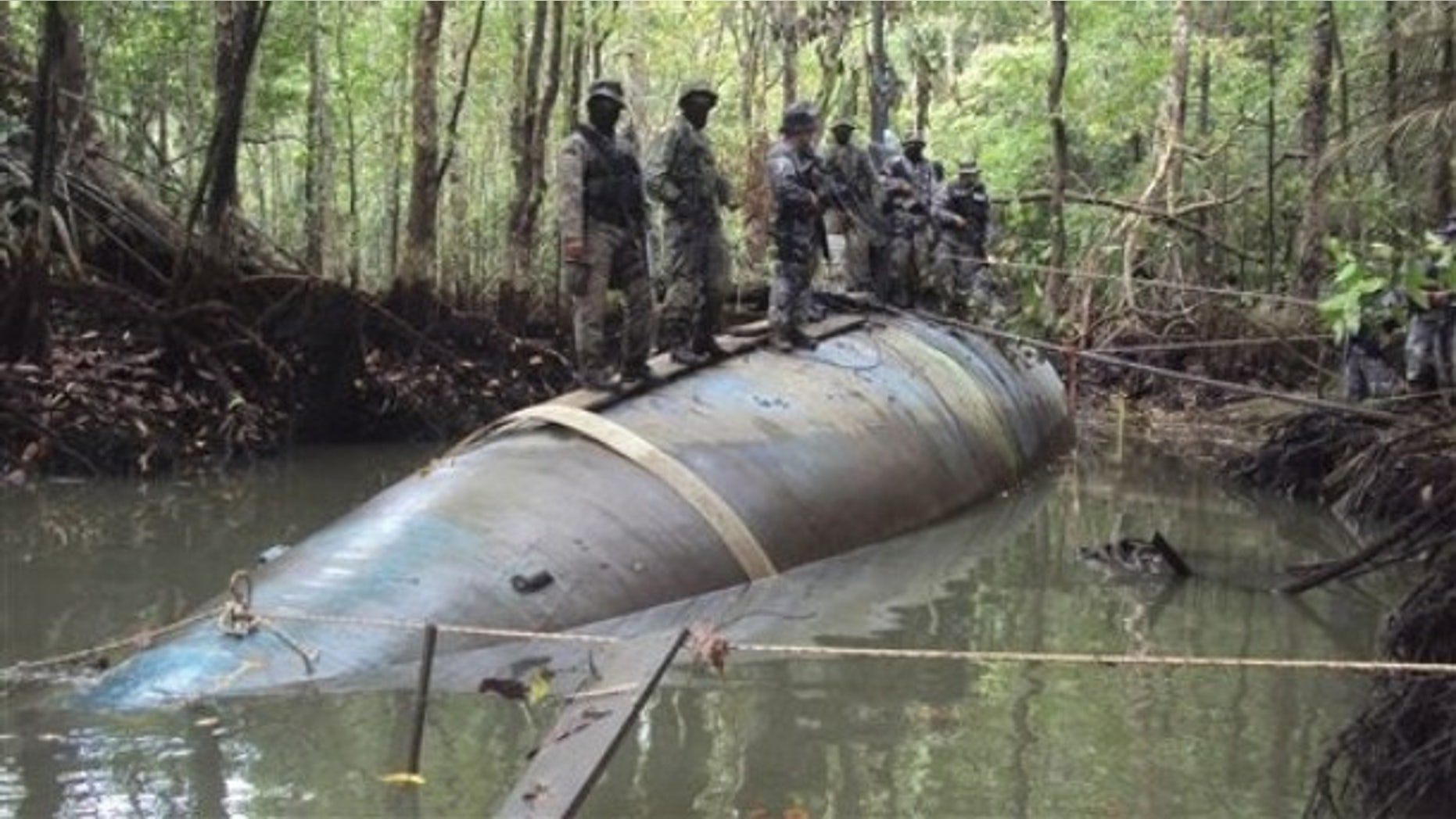Soldiers stand on a seized submarine in the jungle region of La Loma in Ecuador, Saturday July 3, 2010. DEA officials said that the diesel electric-powered submarine was constructed in a remote jungle and captured near a tributary close to the Ecuador-Colombia border and is capable of transporting tons of cocaine.