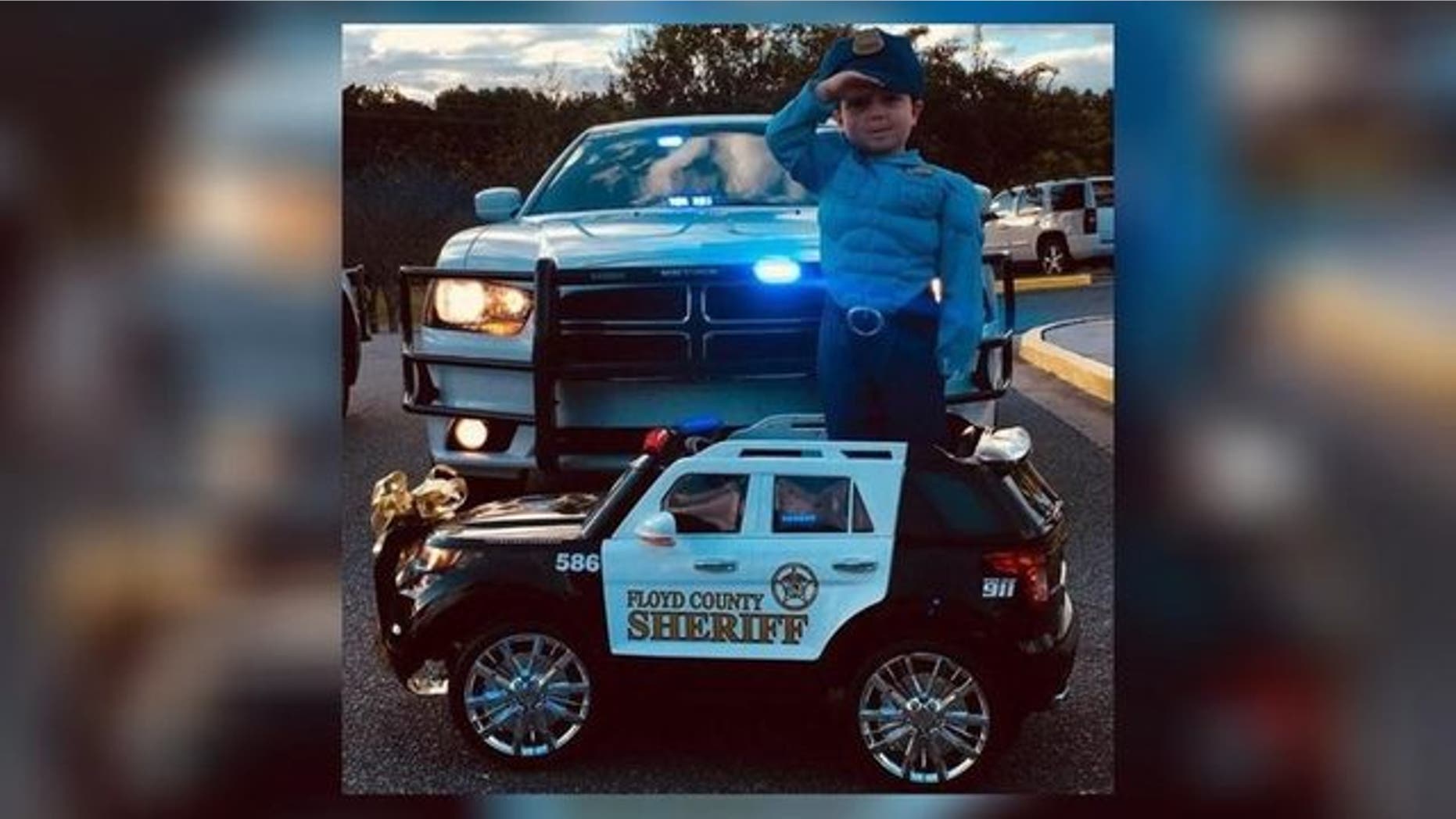 Three-year-old Cohen standing at attention in his electric toy police car.