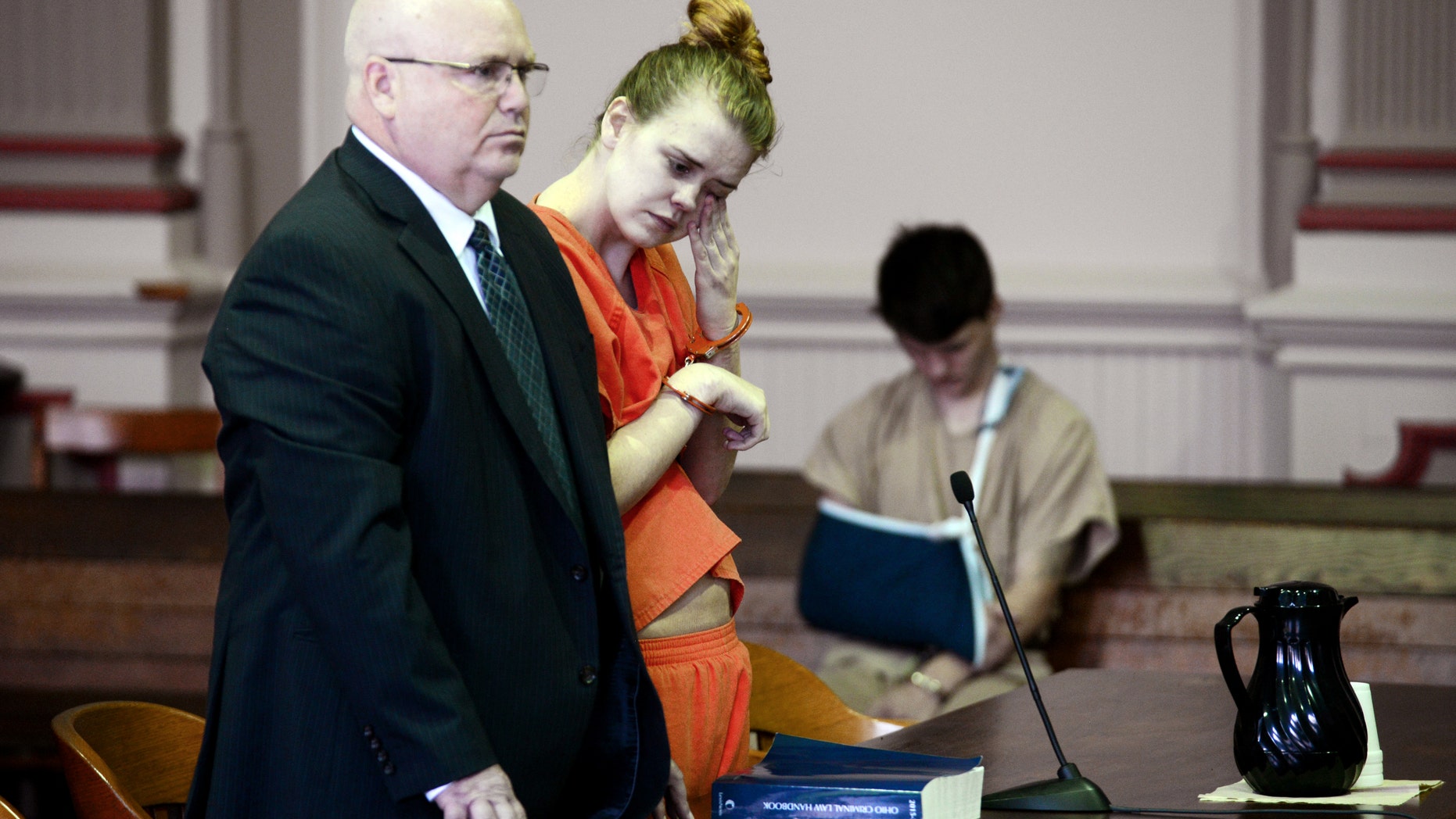 Emile Weaver, center, wipes her eyes while standing next to her attorney.