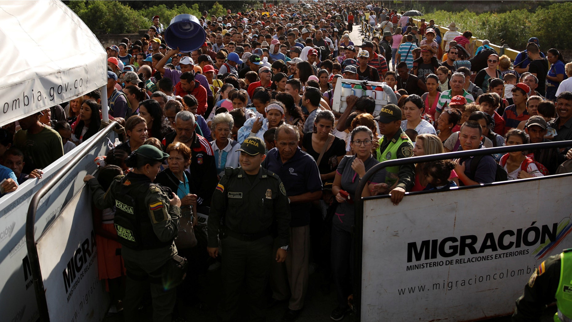 Colombian police officers stand in front of people assembling to try to cross into Colombia from Venezuela last month via Simón Bolívar International Bridge in Cúcuta, Colombia.