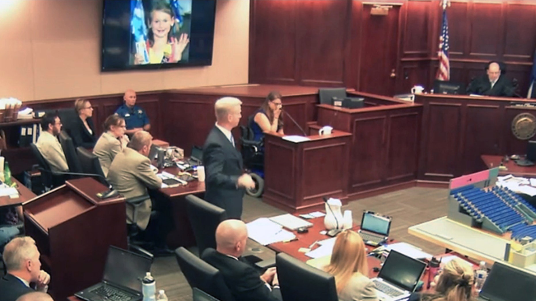 June 19, 2015: In this image taken from video, Ashley Moser, center top, who lost her 6-year-old daughter Veronica in the 2012 Colorado movie theater mass shooting, cries while testifying as a picture of her slain daughter is shown, top, during the trial of theater shooter James Holmes, pictured at top left, in Centennial, Colo. (AP)