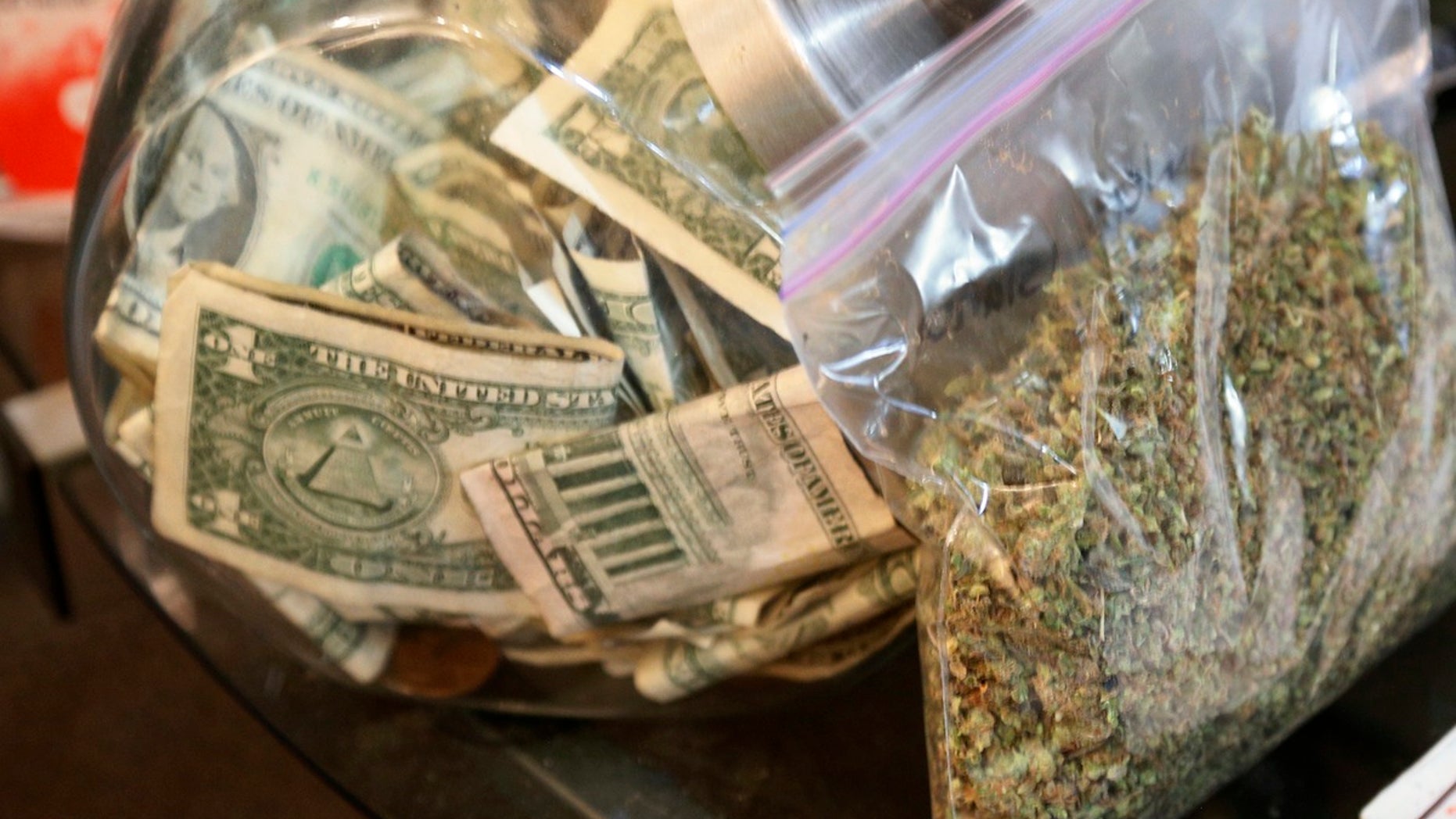 A bag of marijuana being prepared for sale sits next to a money jar at BotanaCare in Northglenn, Colorado.