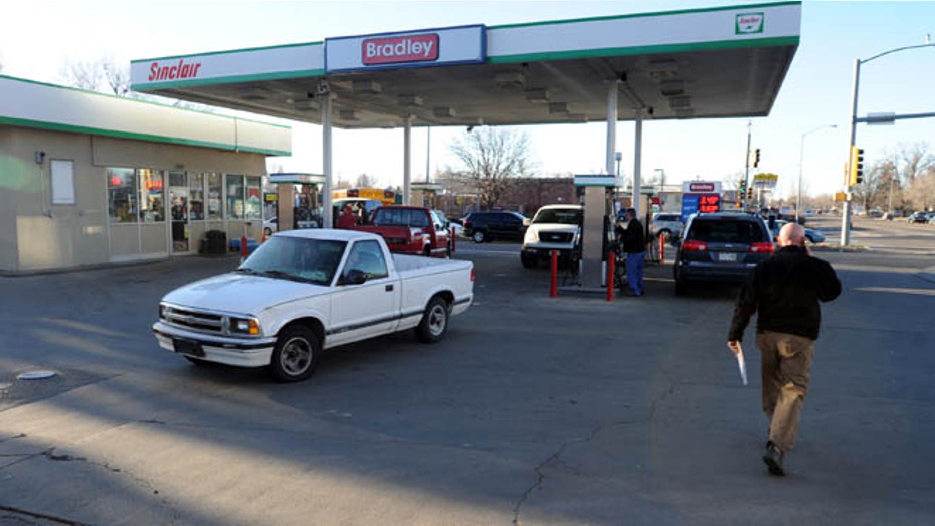 March 12, 2014: Longmont Det. Joel Post, right, talks on the phone outside the Bradley Sinclair gas station where a carjacking occurred in Longmont, Colo.