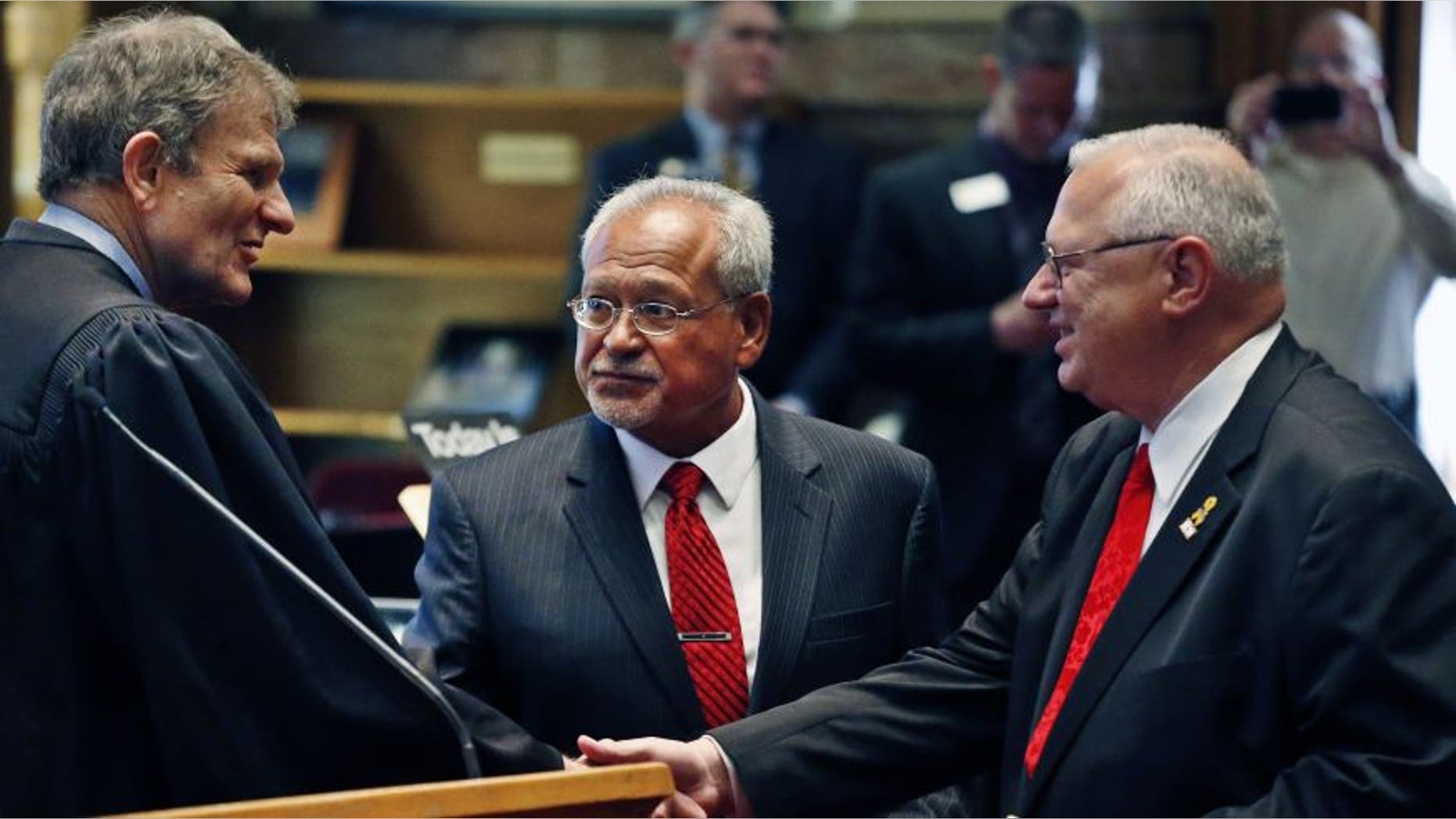 FILE: Oct. 3, 2013: Colorado Supreme Court Chief Justice Michael Bender, left, shakes hands with Republican state senator Bernie Herpin, as state senator George Rivera looks on after the two Republicans were sworn in, having defeated Colorado Democratic senators in a recall over new gun restrictions the previous month