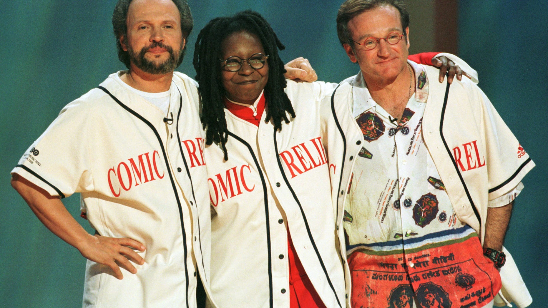 Comedians Robin Williams (R), Billy Crystal (L) and Whoopi Goldberg share a hug on the stage at the end of Comic Relief 8.