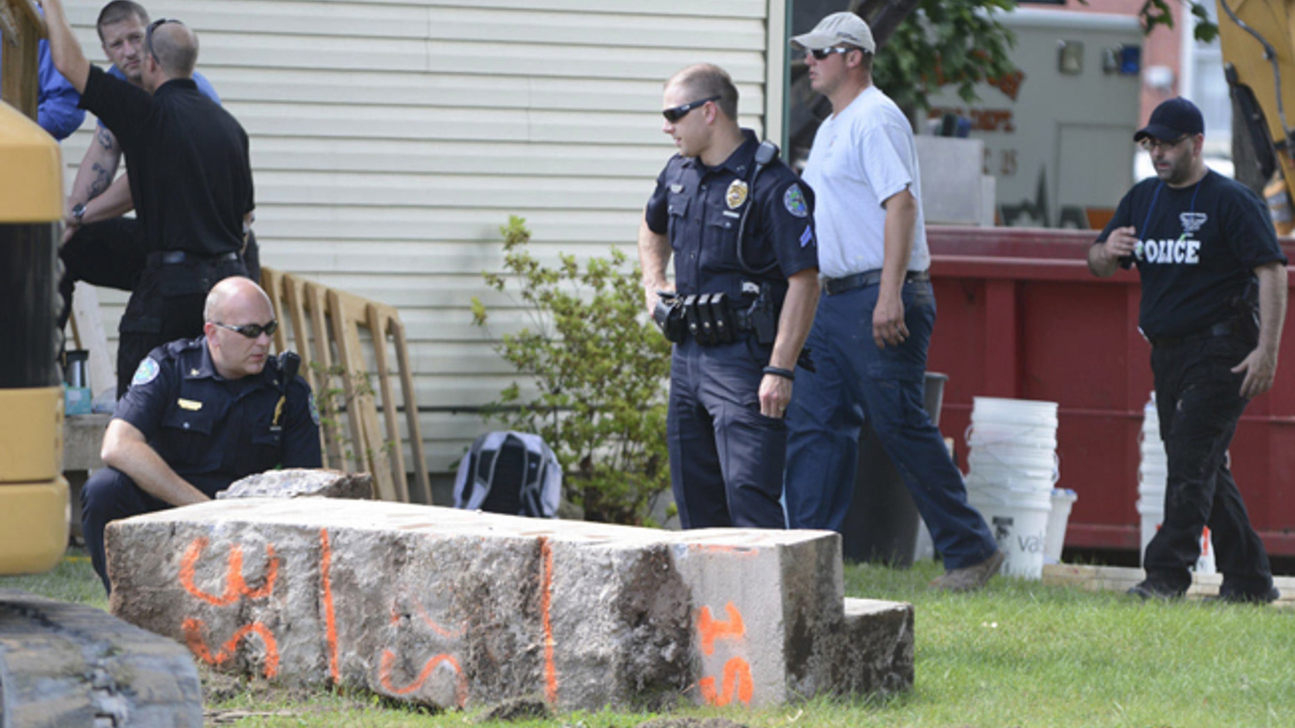 Police officers look over a slab of concrete pulled out of the basement of a home in Milton, Pa.
