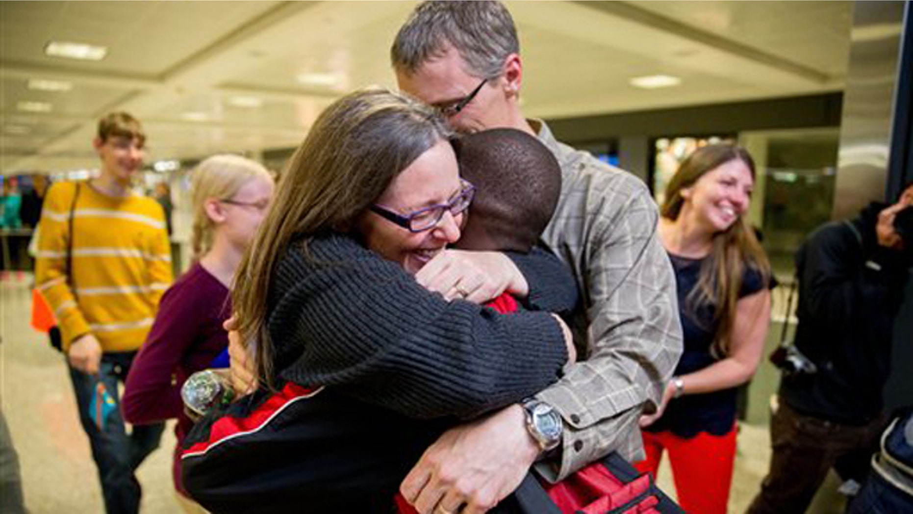 Nov. 11, 2015: Jennifer and Eric Sands of Illinois hug their adopted son Issaac, 12, as he arrives from the Congo at Dulles International Airport.