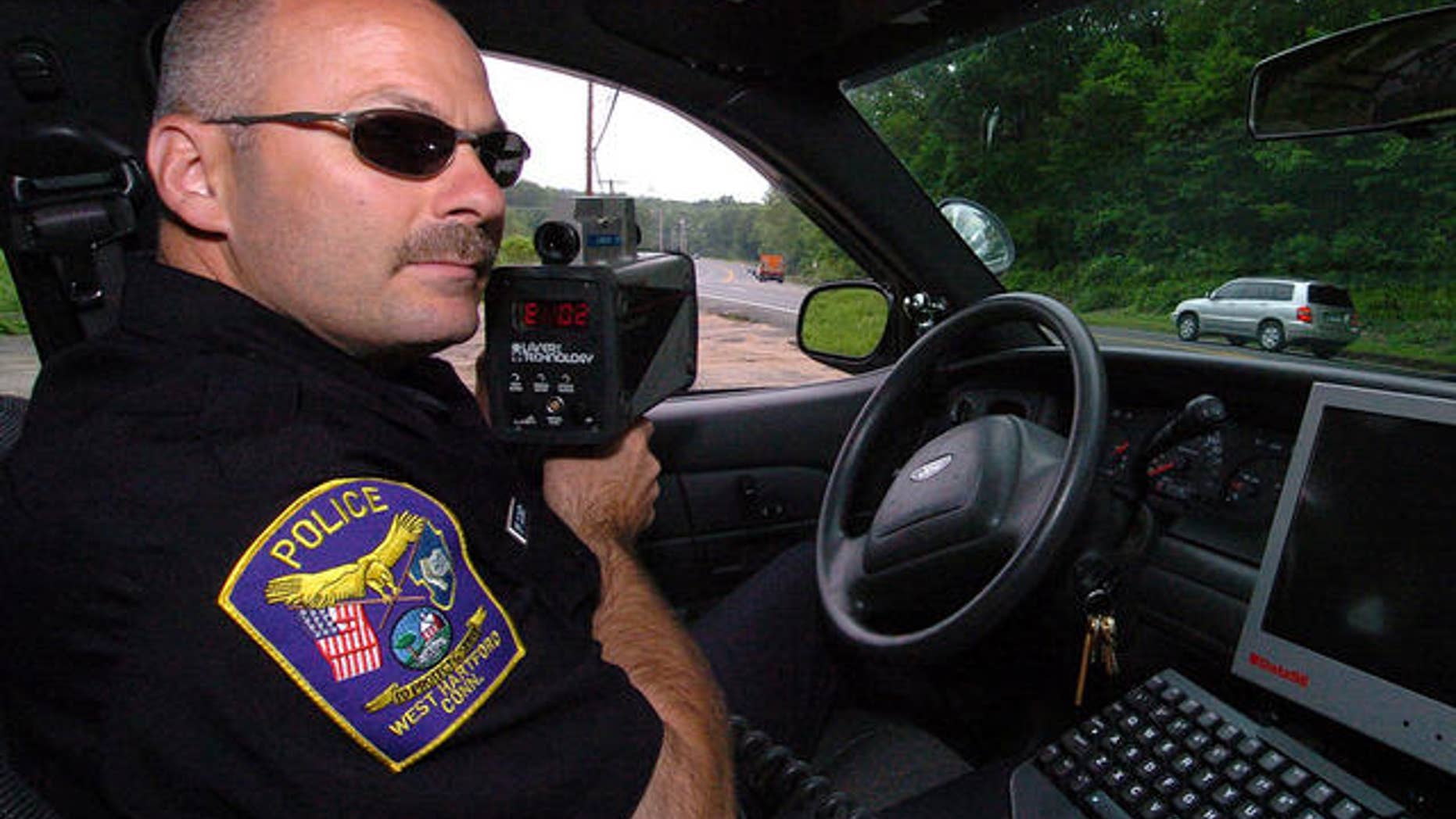** ADVANCE FOR WEEKEND, JULY 1-2 ** West Hartford Police Officer Kerry Cloukey uses a laser unit to detect speeders on Route 44 on Avon Mountain in West Hartford, Conn., Thursday, June 22, 2006. Starting July 1, 2006, a new Connecticut law adds $10 to every ticket issued for speeding, failure to yield, making an illegal turn and dozens of other moving violations. (AP Photo/Jessica Hill)