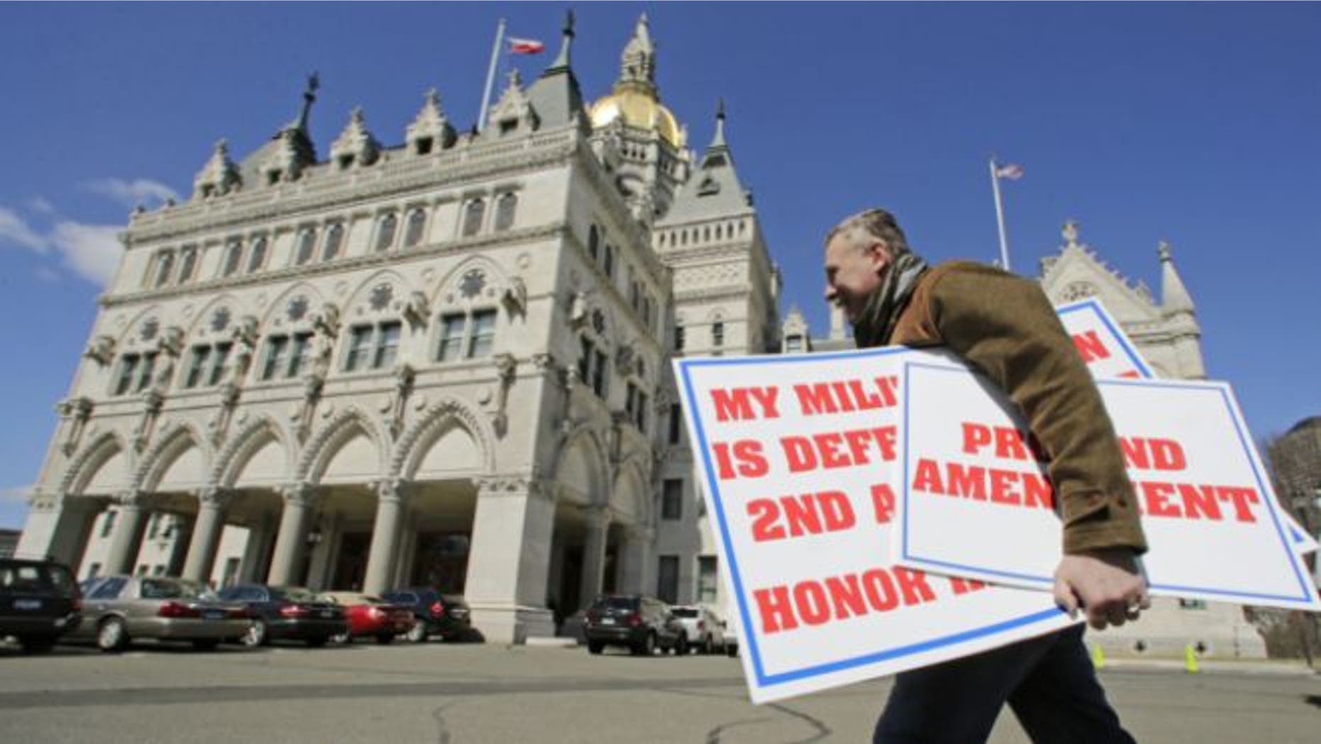 April 3, 2013: Jody Winslow, of Farmington, Conn., carries signs regarding the second amendment of the U.S. Constitution as he heads back to the Capitol in Hartford, Conn.