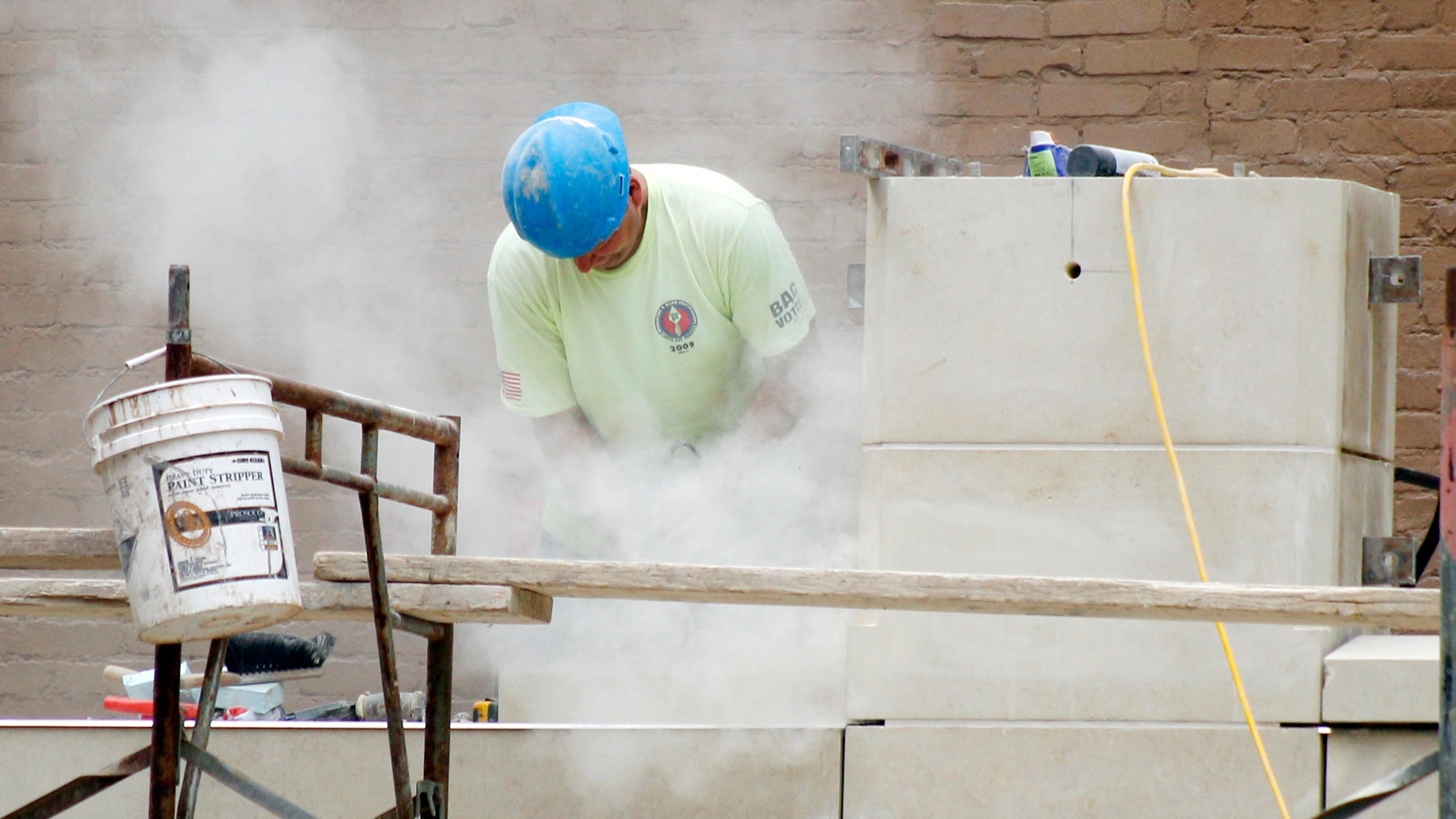 In this July 21, 2011 photo, a workman stands in a cloud of dust as he grinds block for fitment at a construction site at Point Park College in downtown Pittsburgh.