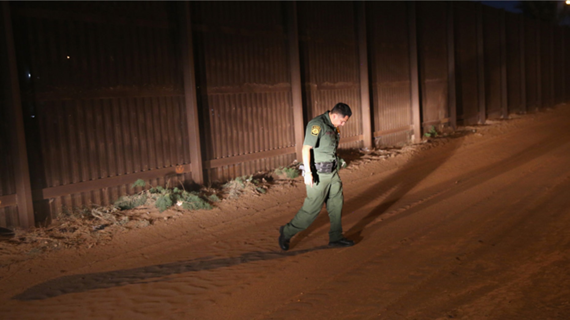 CALEXICO, CA - NOVEMBER 15: A U.S. Border Patrol agent looks for tracks along the U.S.-Mexico border fence on November 15, 2013 in Calexico, California. The fence separates the large Mexican city of Mexicali with Calexico, CA, and is a frequent illegal crossing point for immigrant smugglers. (Photo by John Moore/Getty Images)
