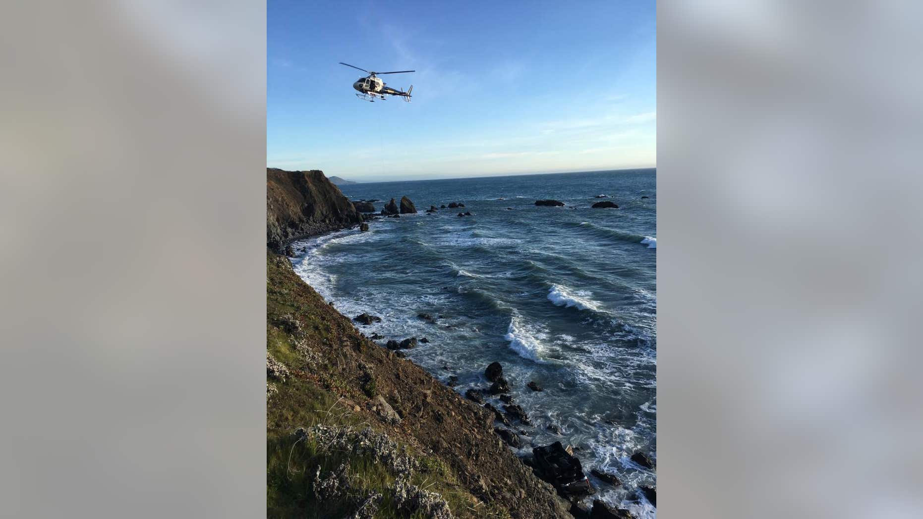 Personnel aboard a California Highway Patrol helicopter inspect the scene where a vehicle plunged off a cliff in California, killing five people, March 26, 2018.
