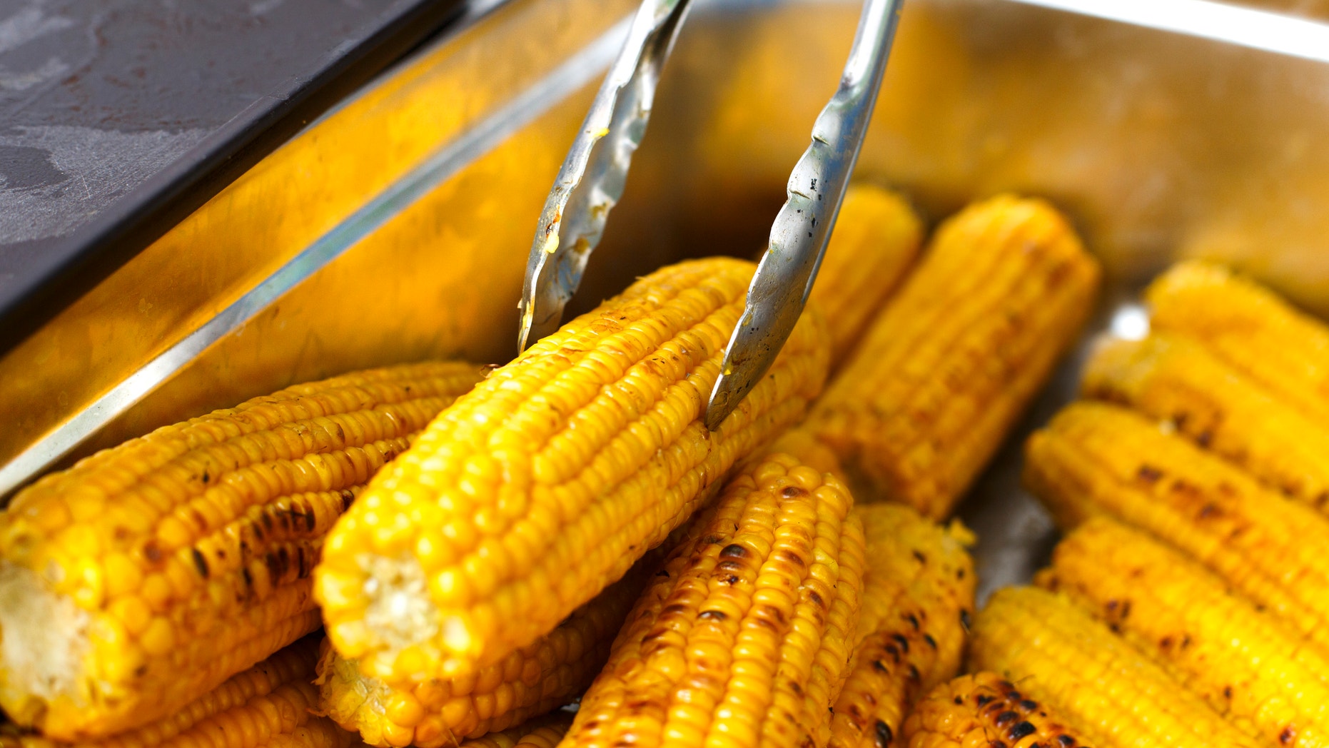Vegan bbq party. Barbecue corns outdoors. Cookout bbq vegetable food. Fresh organic, healthy vegetarian grilled snack, corncobs cooked on grill. Street food, fast food. Tasty natural food.